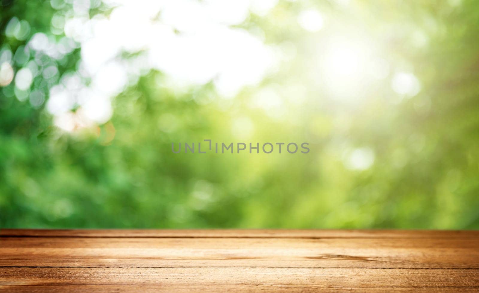 Blank country fence plank, table top or counter bar with abstract green forest trees background. Nature bokeh sunlight. Mock up, product template. Banner or header for advertise on social media