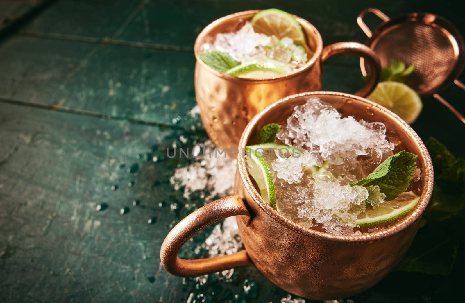 From above of tasty Moscow mule beverages with ice and lime served in copper mugs on dark wooden table in kitchen