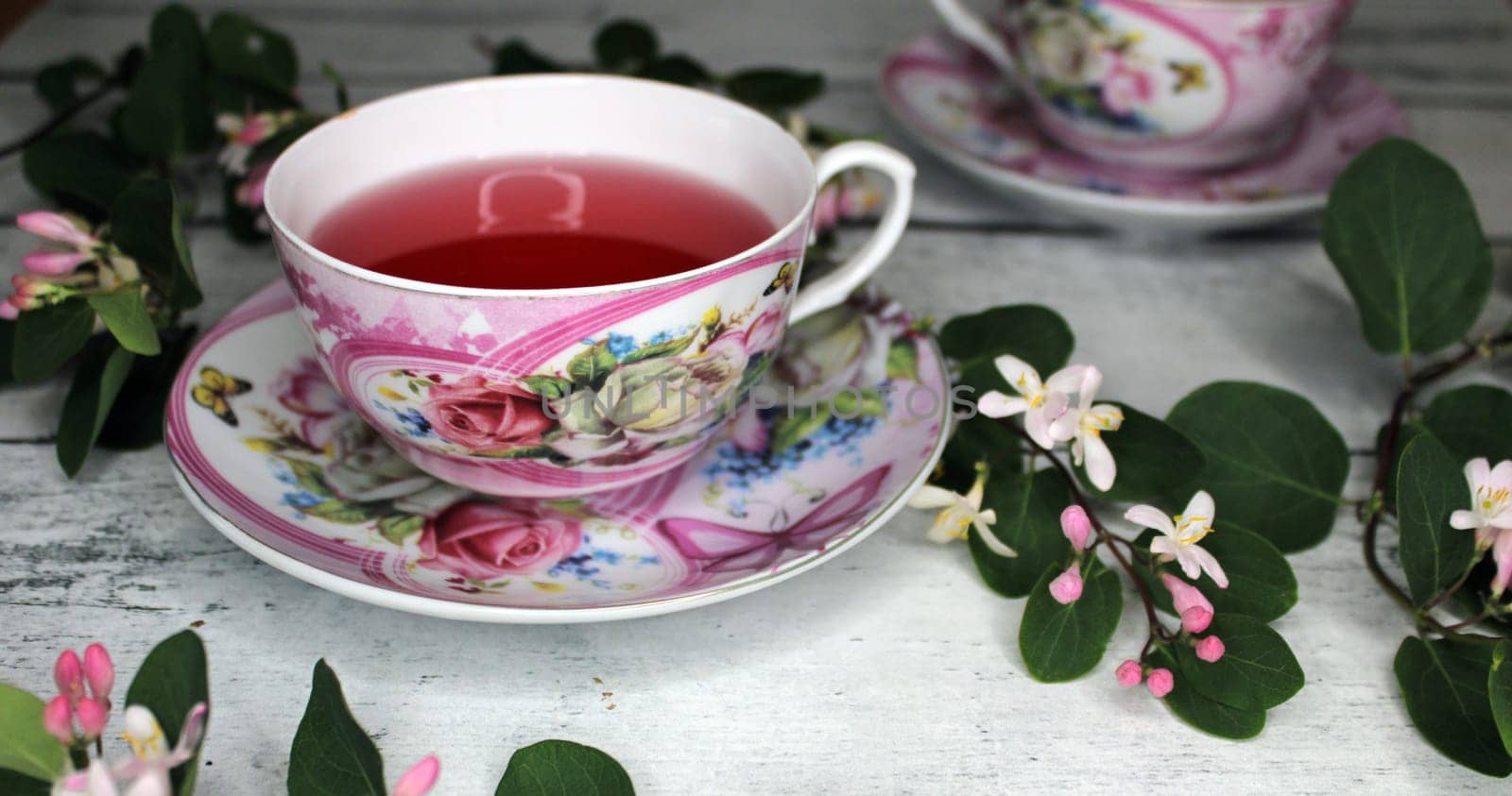 Two cups of tea with flowers on a wooden table..