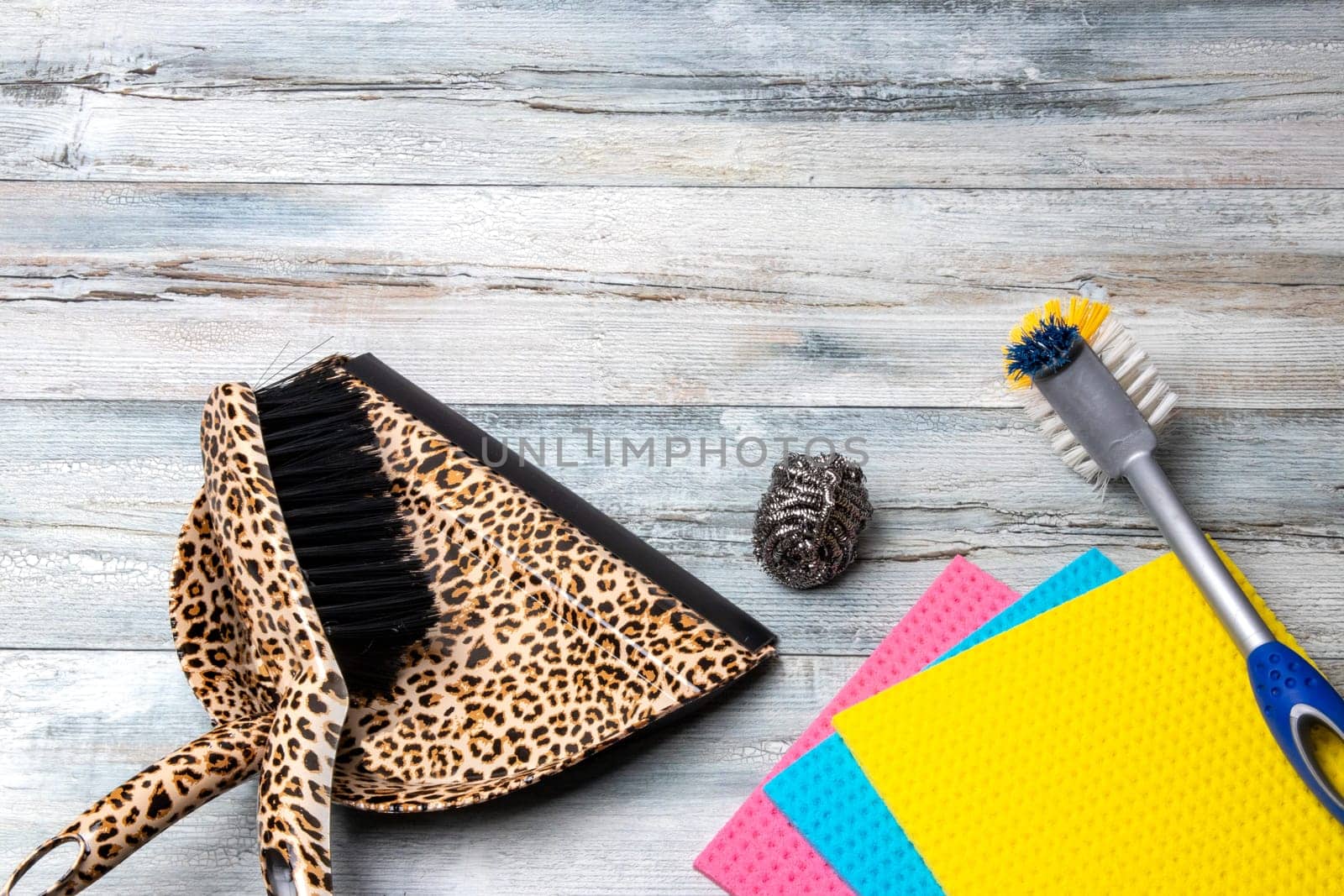 Household cleanliness and hygiene. A dustpan and hand brush and other cleaning tools on a light rustic table. Space for design. Household chore concept.