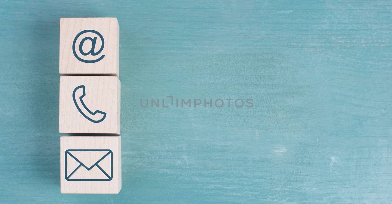 Signs for e-mail, phone and newsletter on wooden blocks, blue background, copy space for text, business support and communication concept
