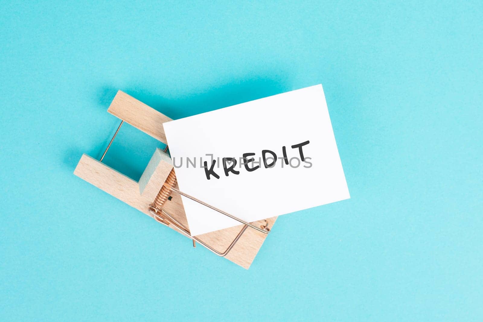 Paper with the word credit in german language in a mousetrap, finanicial debt, inflation, risky credit and investment, bank loan