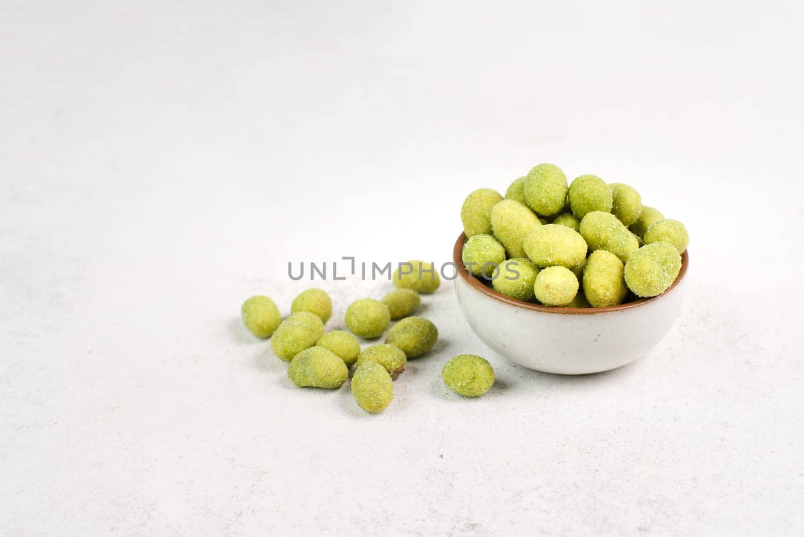 Pile of green wasabi coated peanuts in a bowl, spicy snack, oriental food