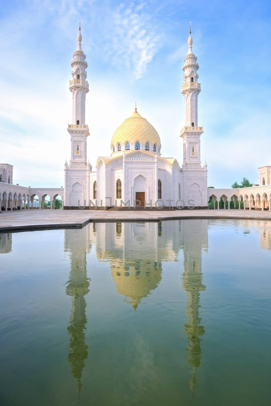 White Mosque, Bolgar, Tatarstan. A beautiful white mosque with domes and minarets against a bright blue sky. In the foreground is a reflection in the water.