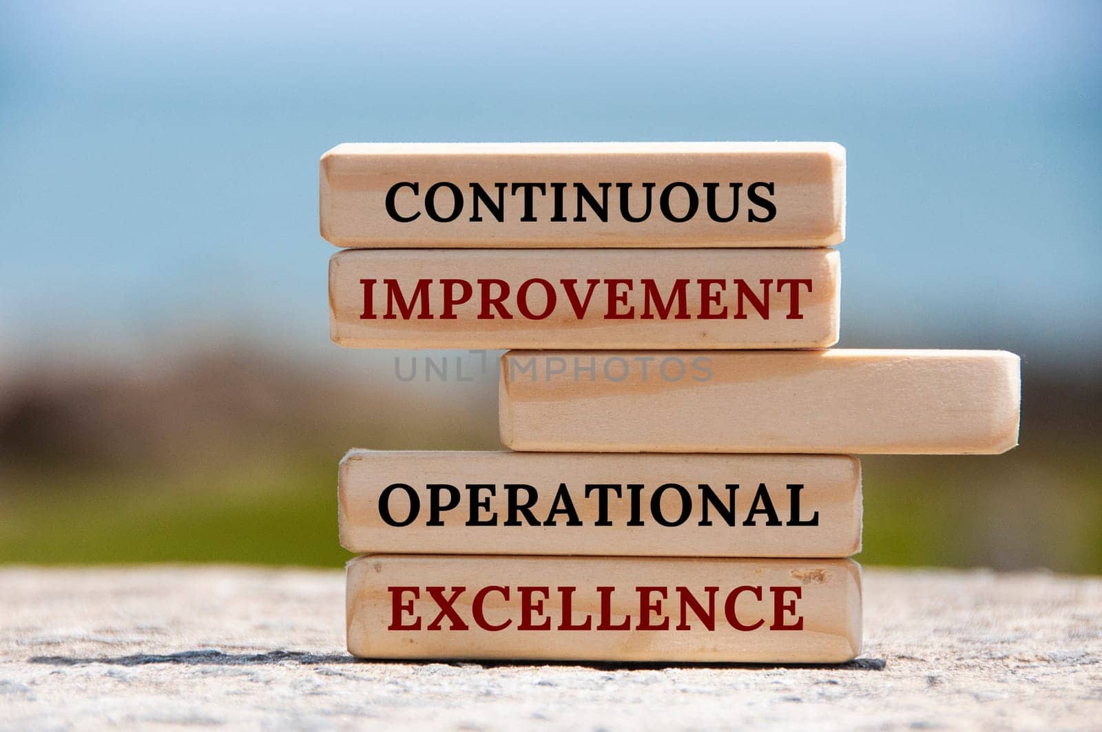 Continuous improvement Operational excellence text on wooden blocks with blurred nature background. Business concept