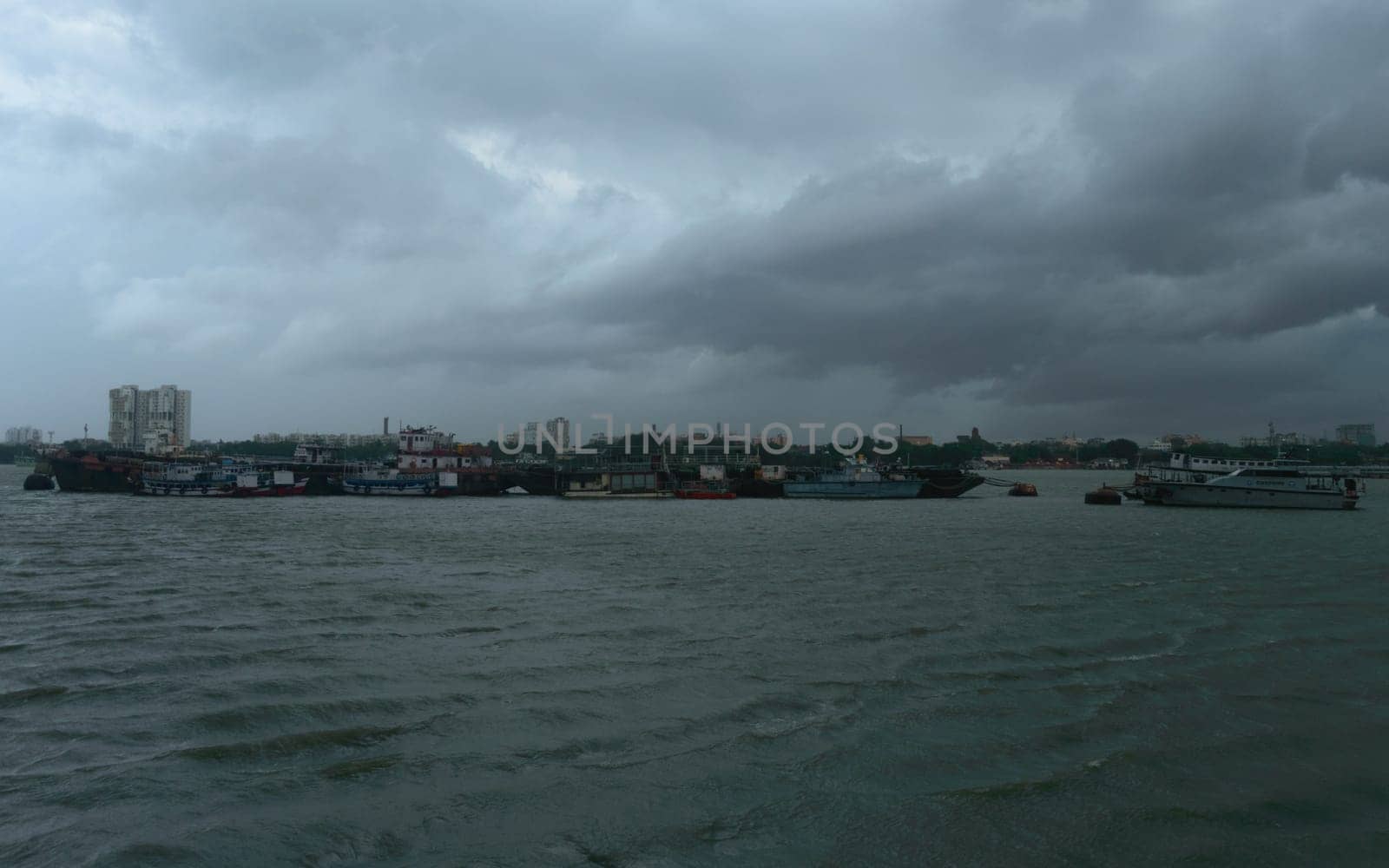 Ferry Boats floating over Ganges River at a distance on a Dramatic cloudy day. Beautiful Landscape View horizon from Babu Ghat. Kolkata West Bengal India South Asia 19 June 2022