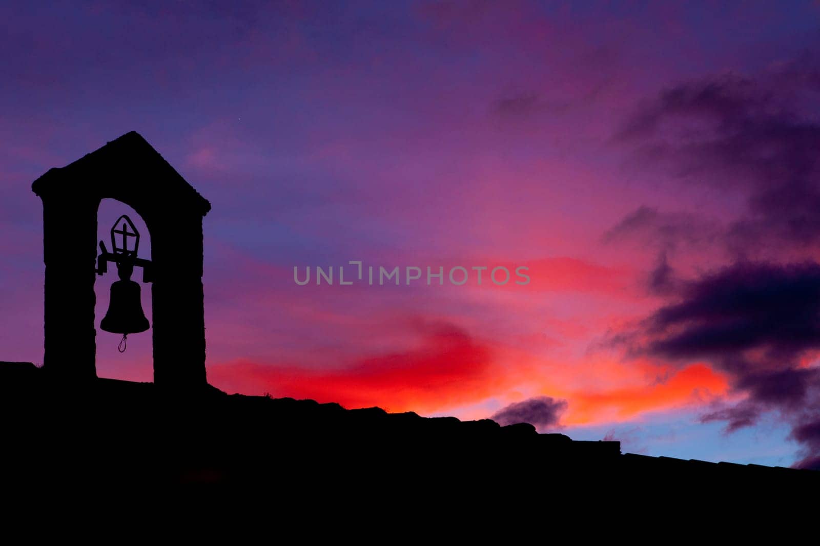 silhouette of Old belfry lighted with the last ray of light at sunset , Montanchez, Spain