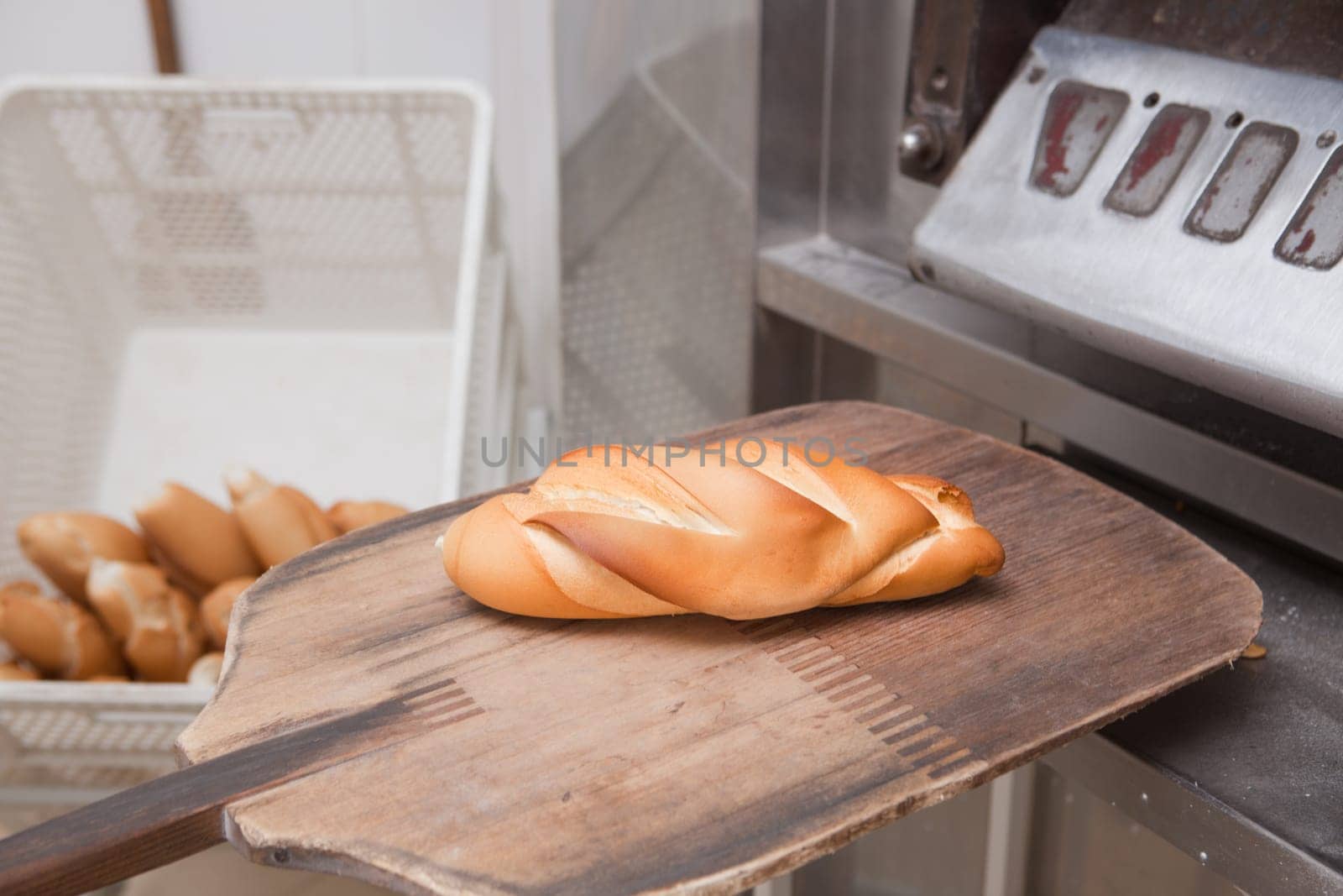 Baker slice with a piece of fresh baked bread. Manufacturing process of spanish bread
