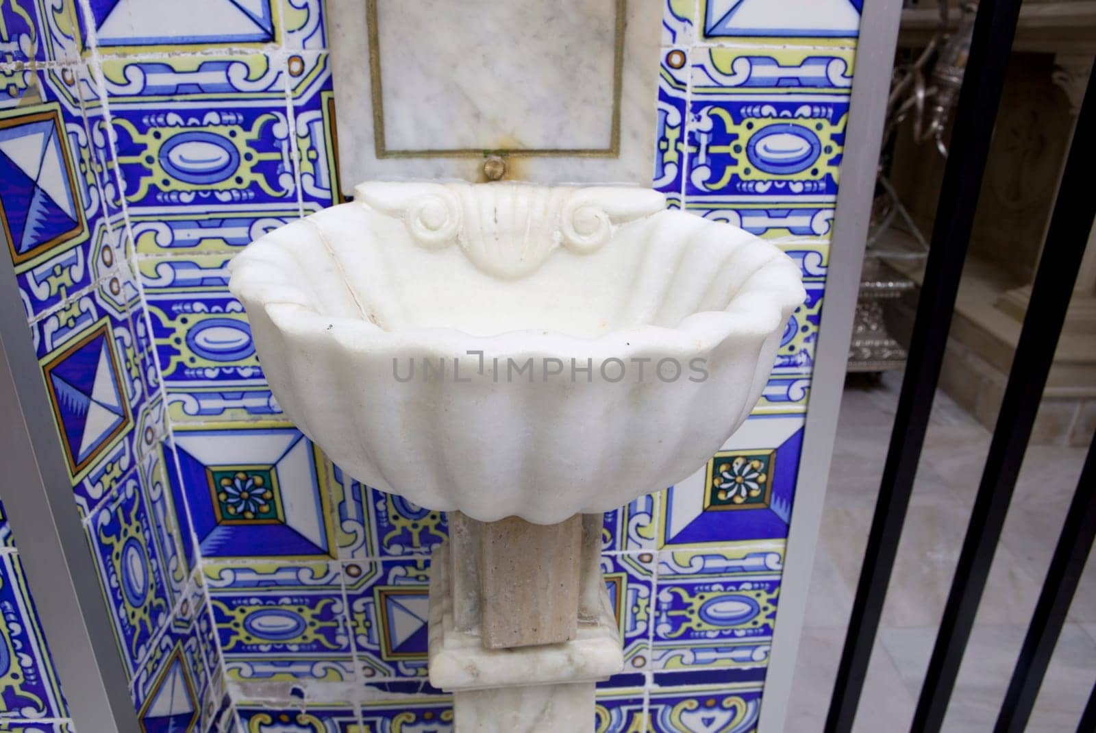 White marble baptismal font over typical spanish glazed tile decoration