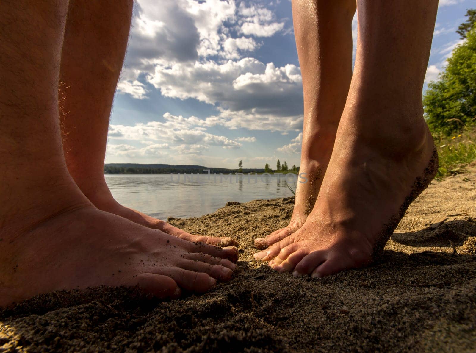 Male and Female Feet in Sand by swedish lake.