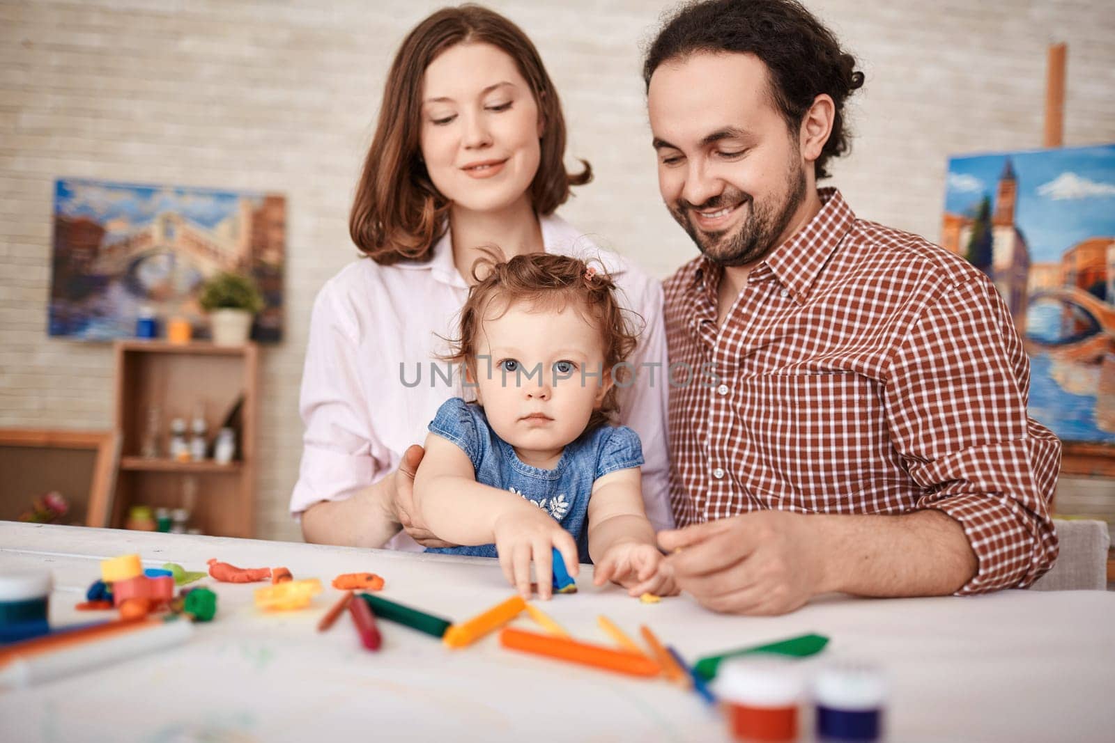 Young parents and pretty daughter playing together