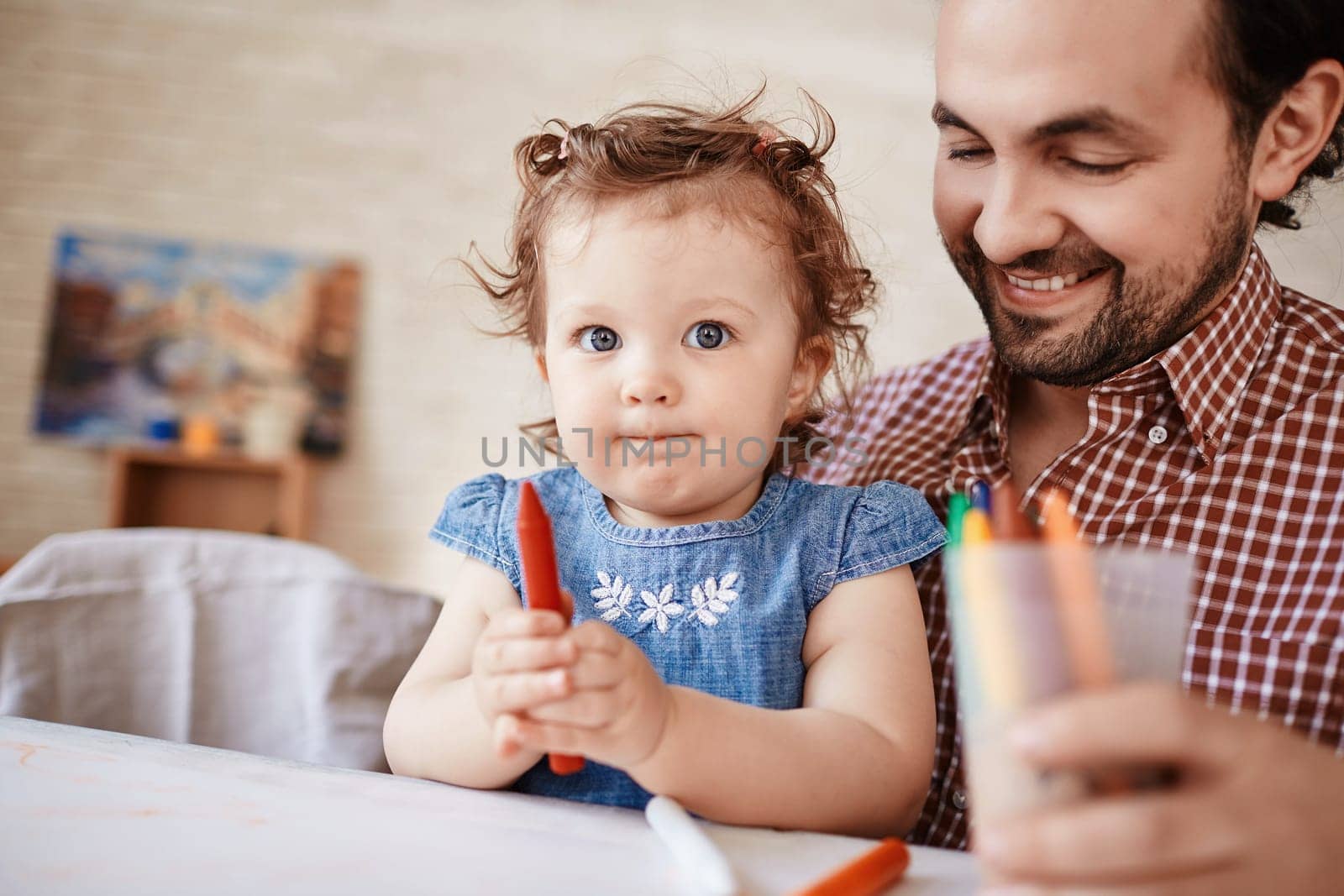 Handsome man and his small daughter with crayon