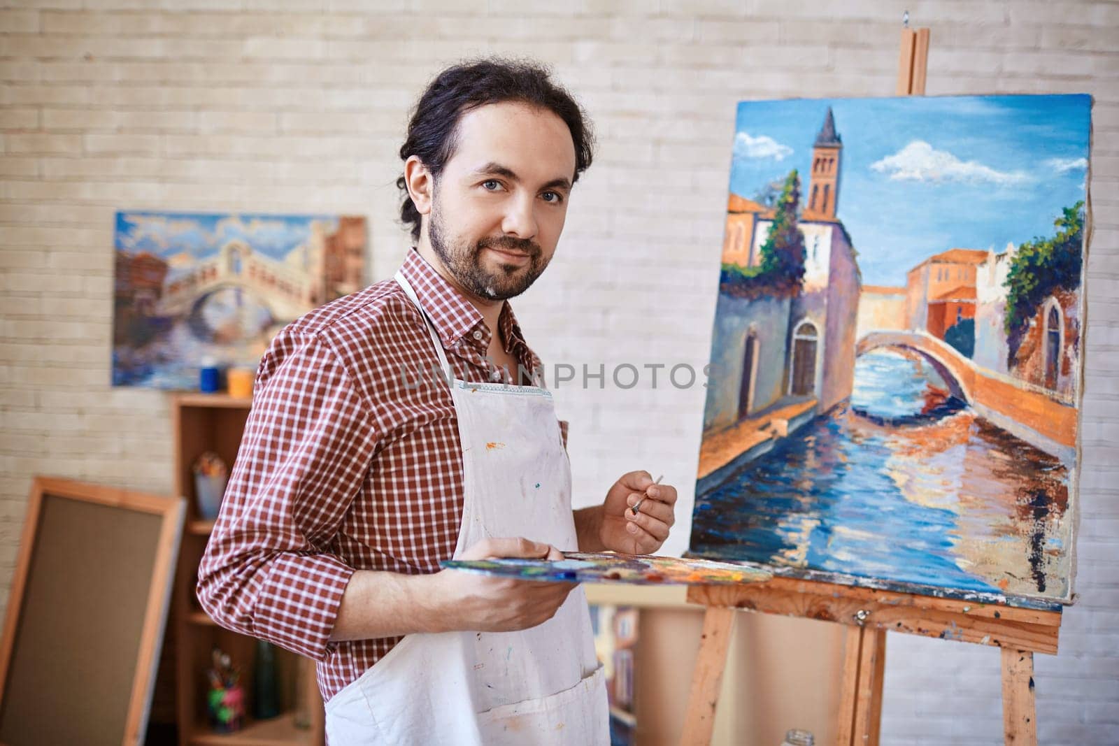 Young artist looking at camera on background of his painting