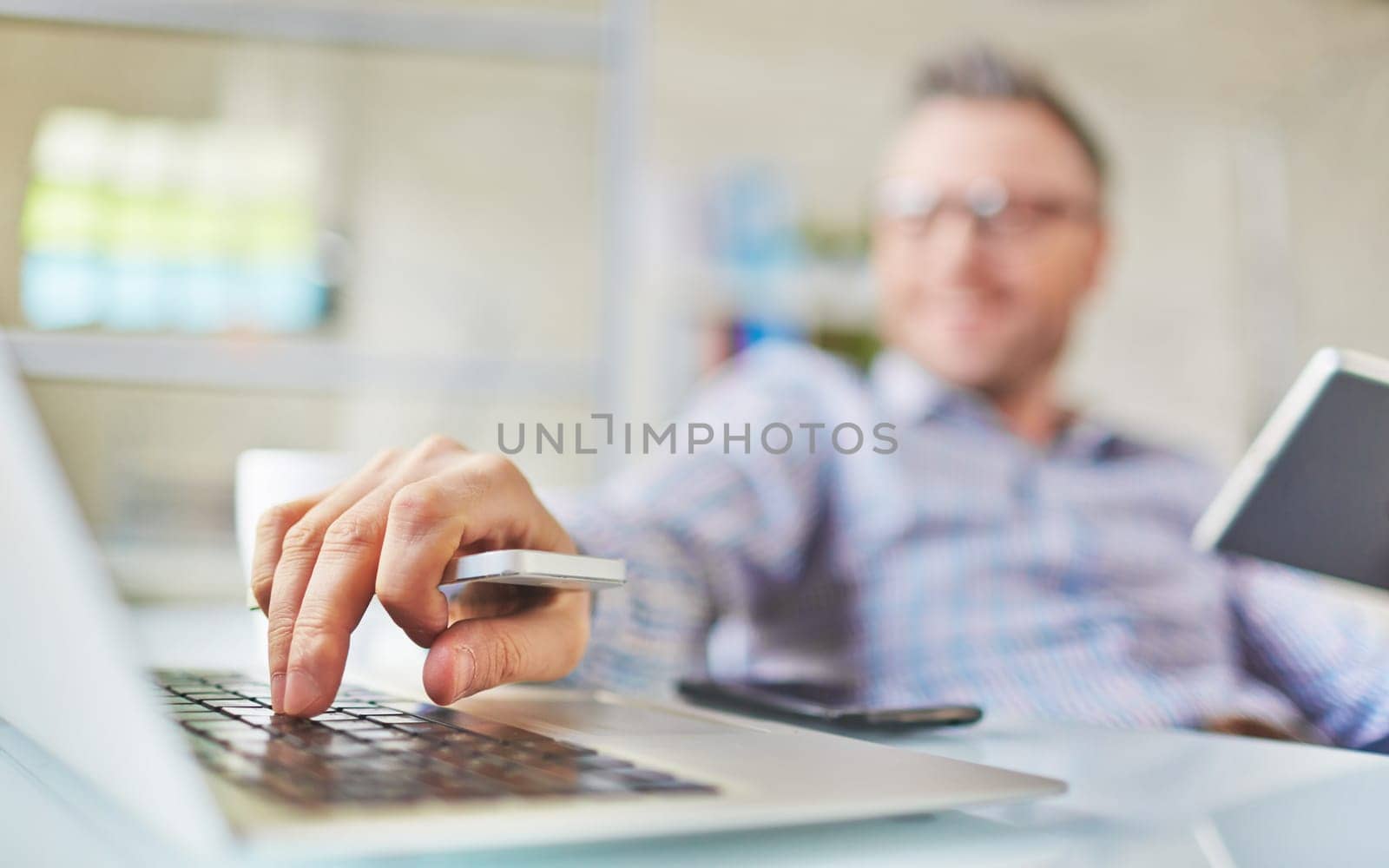 Male hand with cellphone over laptop keypad