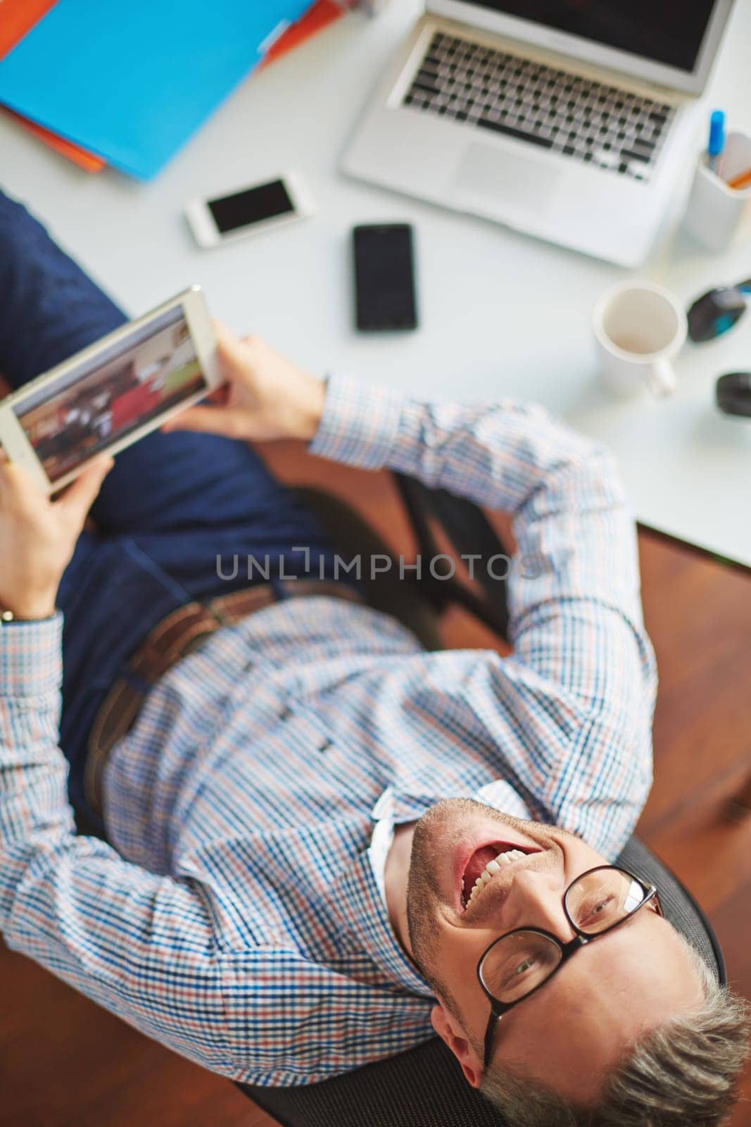 Ecstatic businessman with touchpad sitting by his workplace