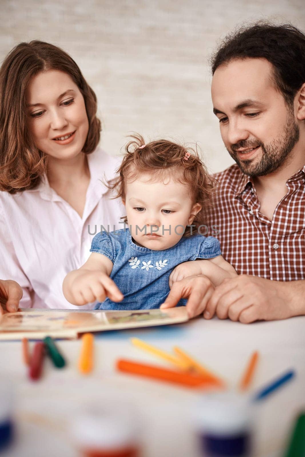 Young couple and little girl reading together