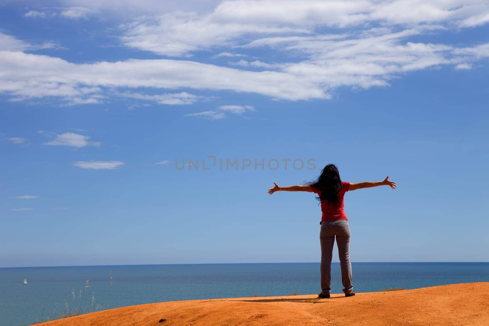 young happy woman at the coast with open arms