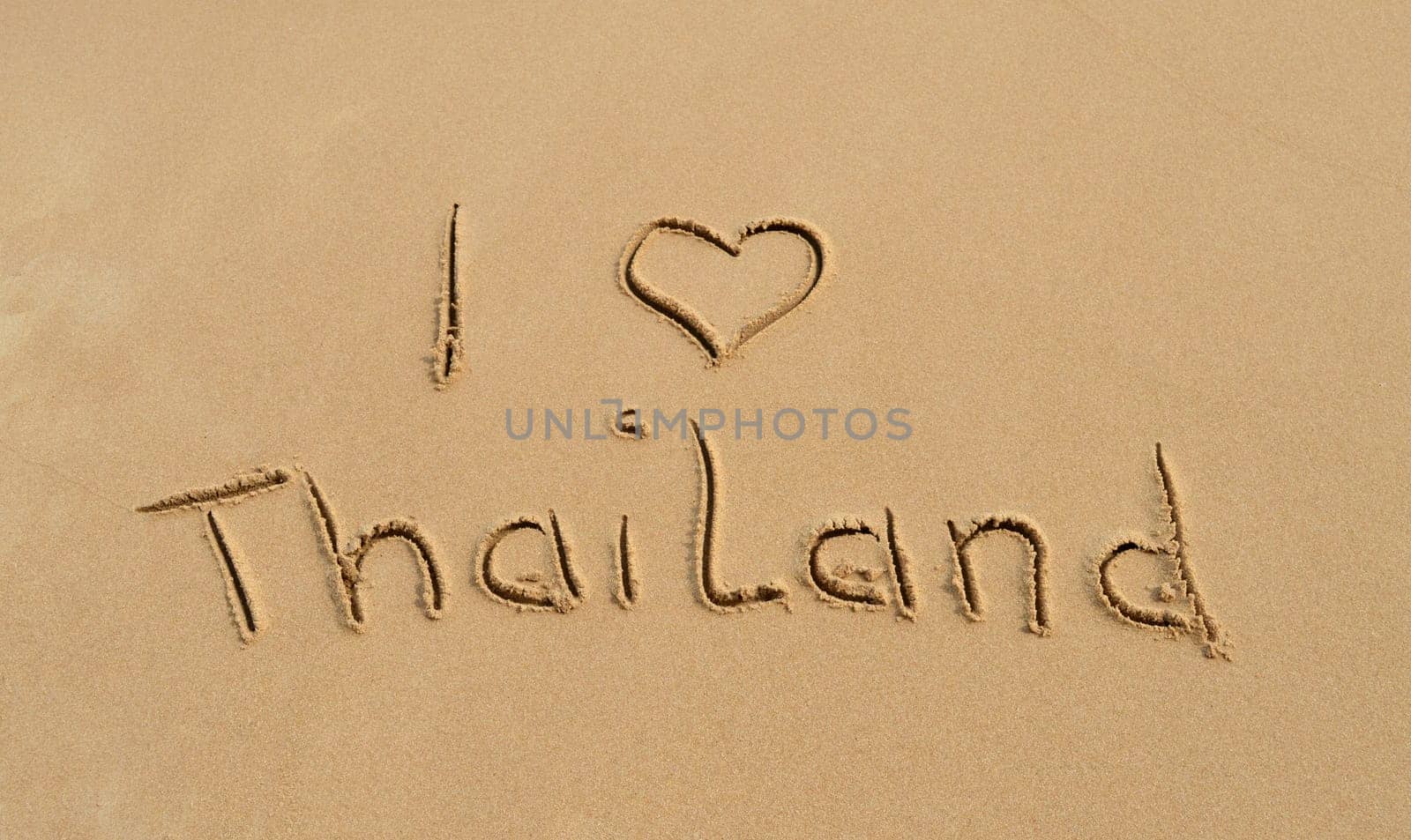The text 'I love Thailand' written in the sand at a tropical beach..