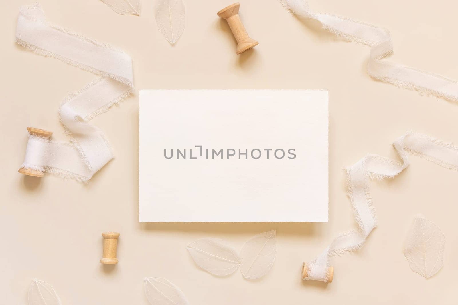 Wedding Card near white silk ribbons on light yellow top view, mockup. Romantic scene with horizontal blank card flat lay. Valentines or Spring romantic concept