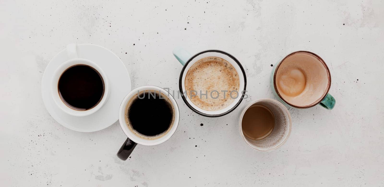 Top view on flat lay with many different full and empty coffee cups composition on gray white concrete background. Variety of tea mug collection layout. Dried coffee beans. Espresso, latte, americano