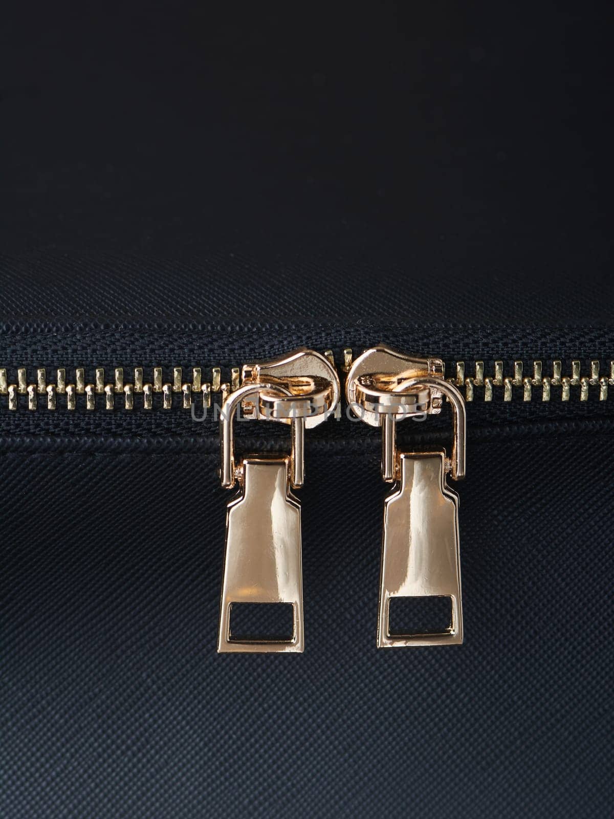golden zippers with golden zippers are fastened on a black leather object close-up. High quality photo