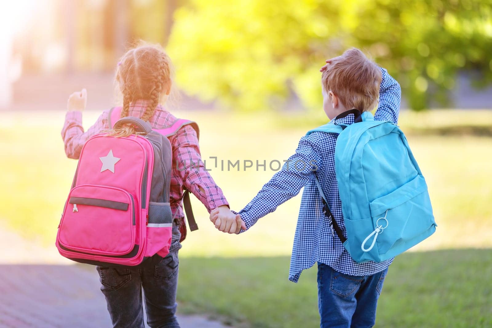 Girl and boy going to the school holding hands to study at it. Concept of back to school and friendship.
