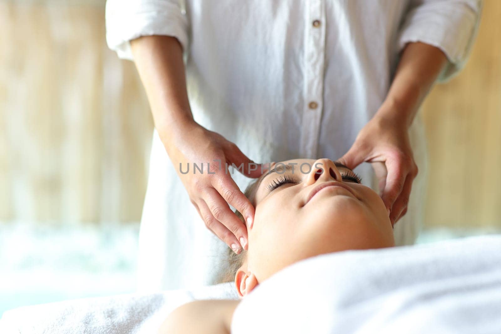 Relaxed woman receiving a facial massage by therapist in spa