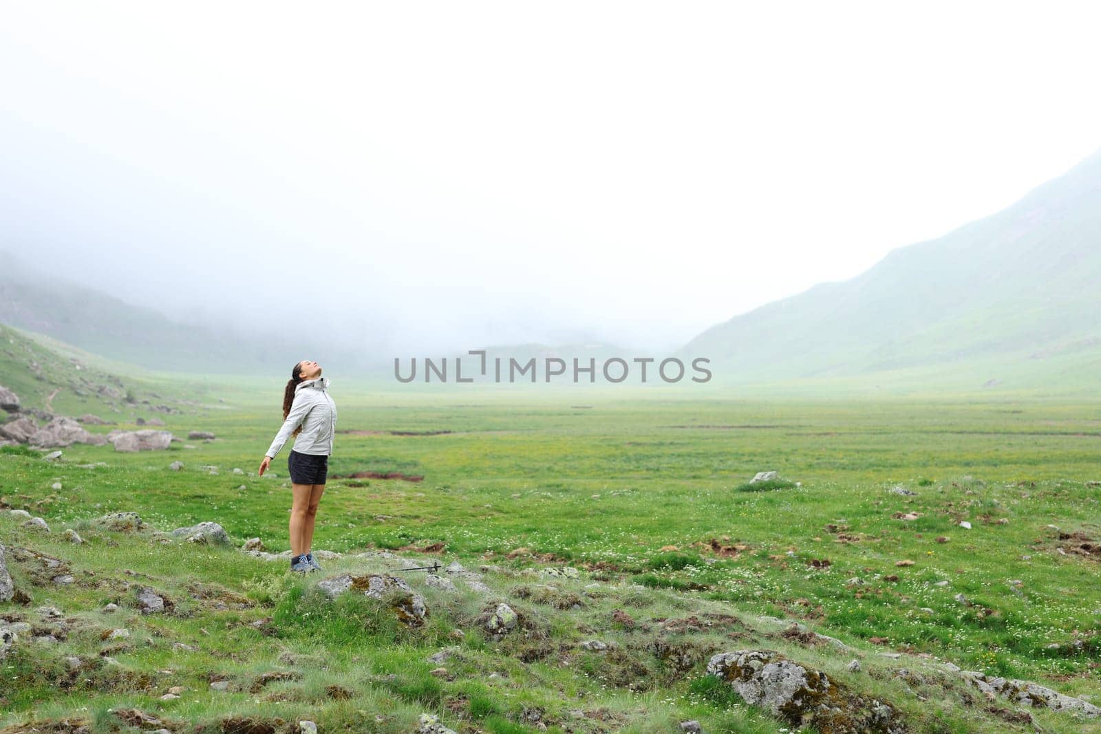 Full body portrait of a trekker breathing fresh air in the mountain a foggy day