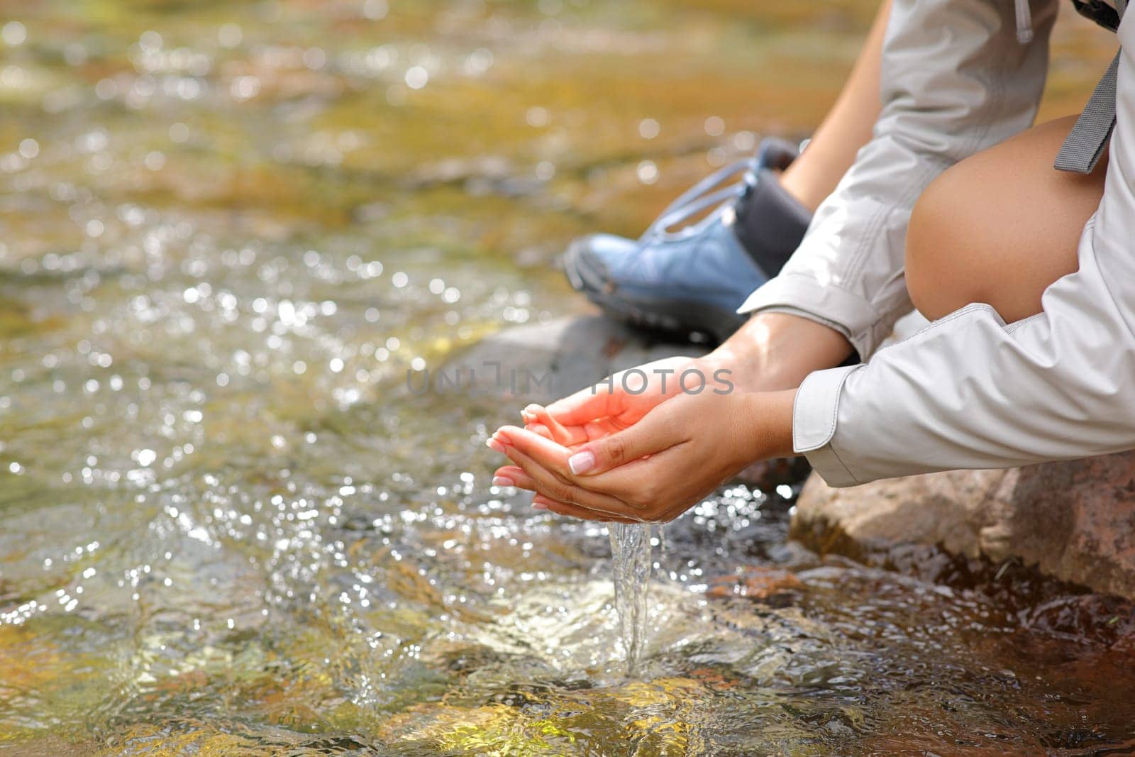 Close up of a woman cupped hands catching water from river