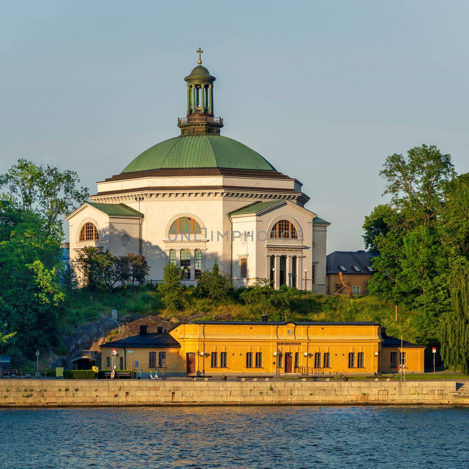 Eric Ericsonhallen concert hall, formerly Skeppsholmen Church until 2009, surrounded by trees. View from Stockholms strom in a sunny summer day, Stockholm, Sweden