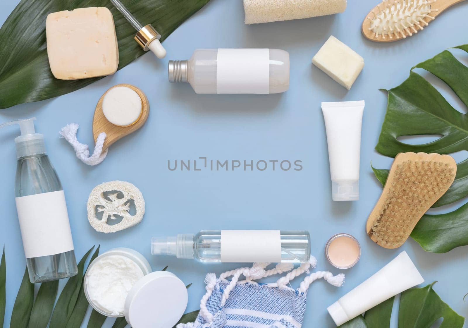 Homemade Cosmetics, eco friendly accessories, and tropical leaves on blue flat lay, copy space. Brand packaging mockup. Natural beauty products for hair and skin care, Top view