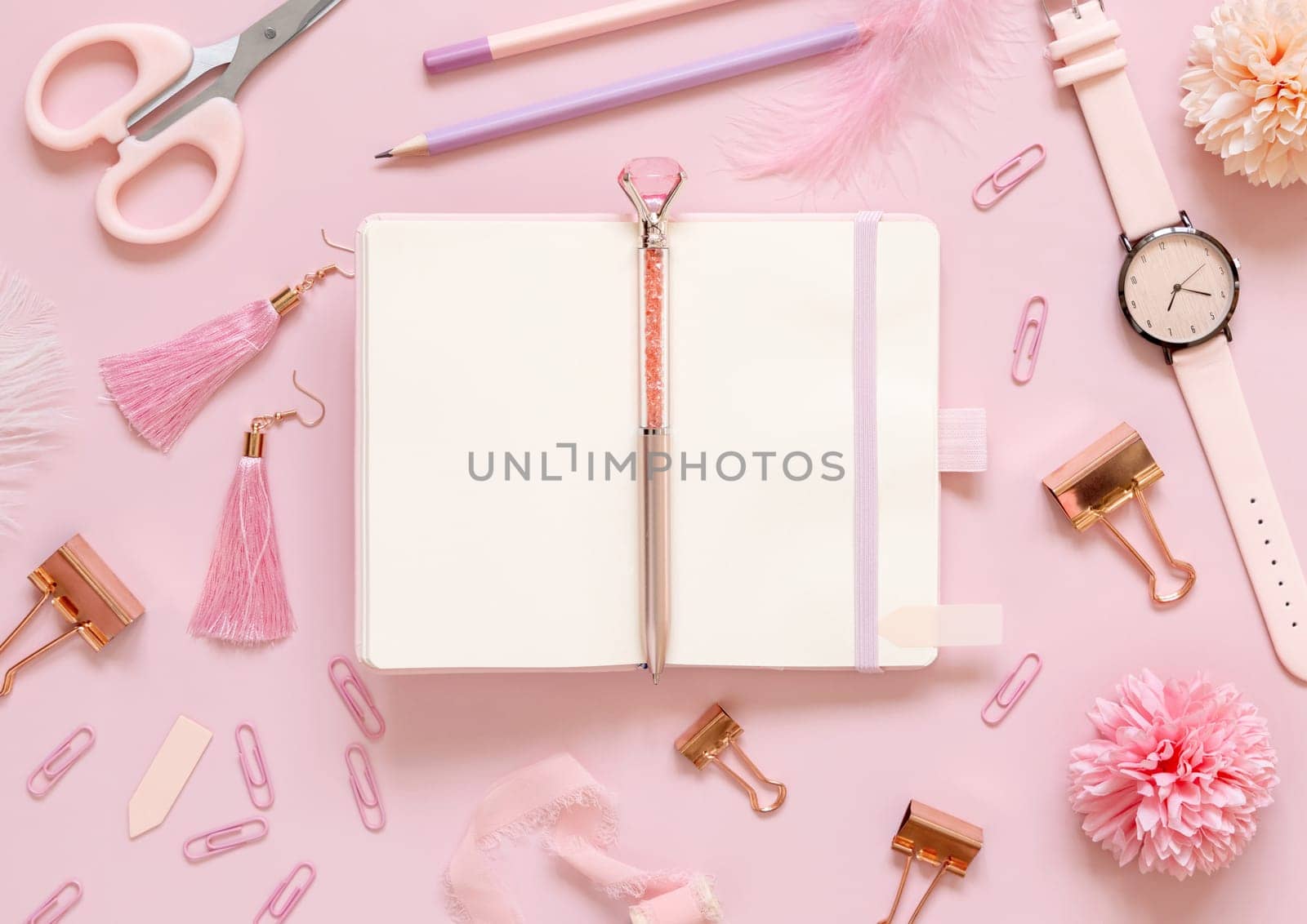 Opened notebook and Pink school accessories on pastel pink, Top view, textbook mockup. Girly workplace with scissors, pencils, pen, paperclips, earrings and watch. Back to school concept