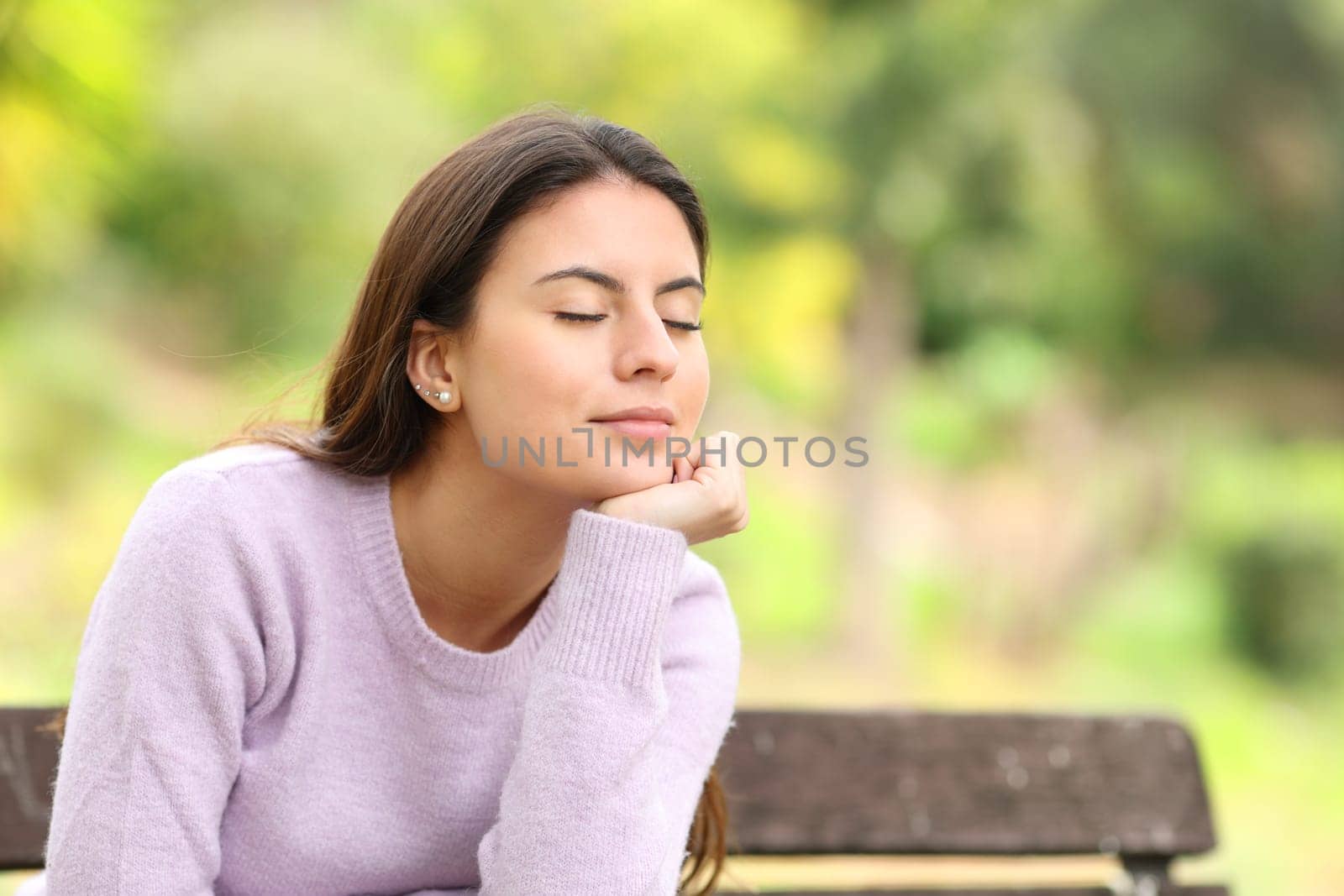 Teen relaxing and resting sitting on a bench in a green park