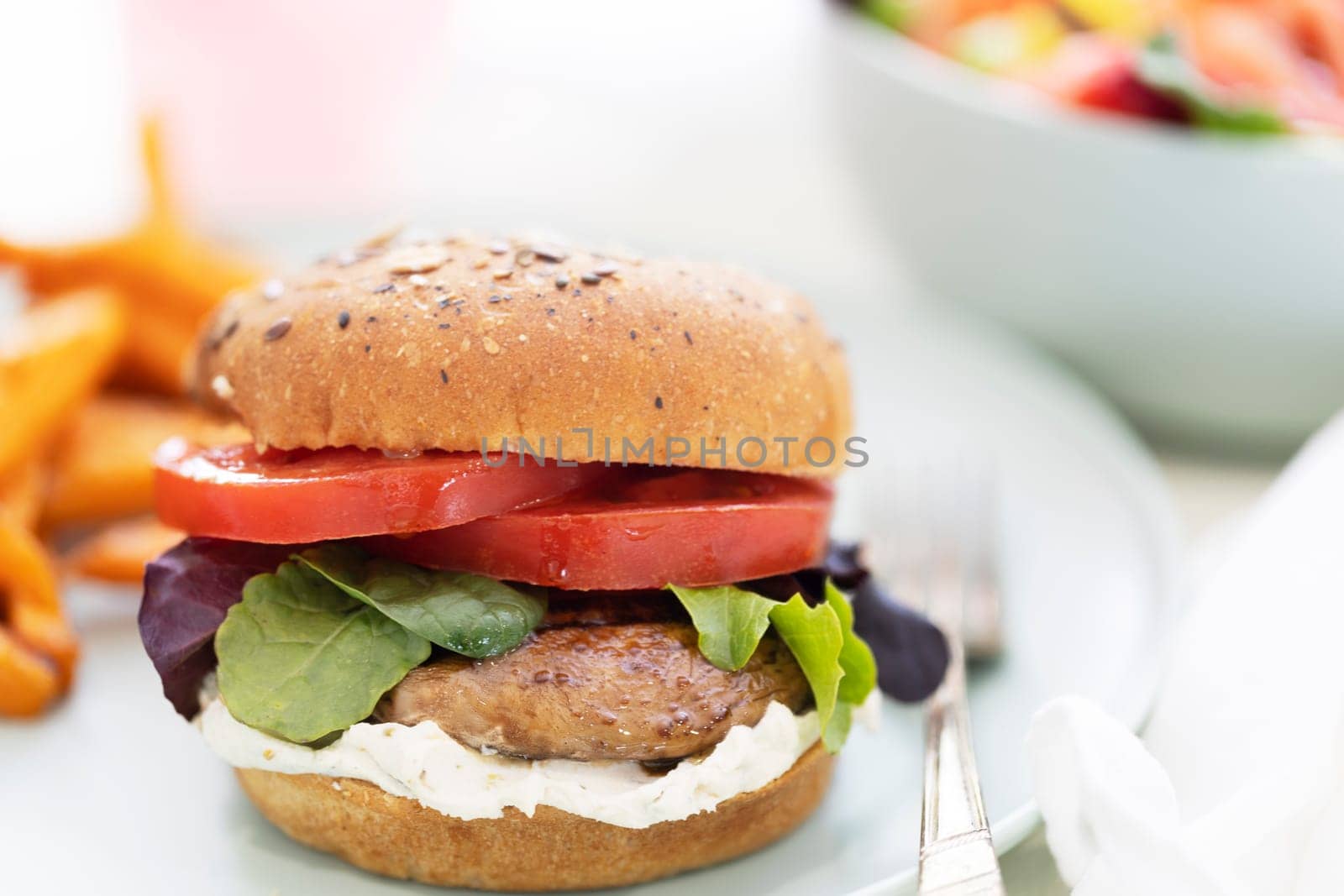 Grilled portobello mushroom burger on whole wheat bun with sweet potato fries.