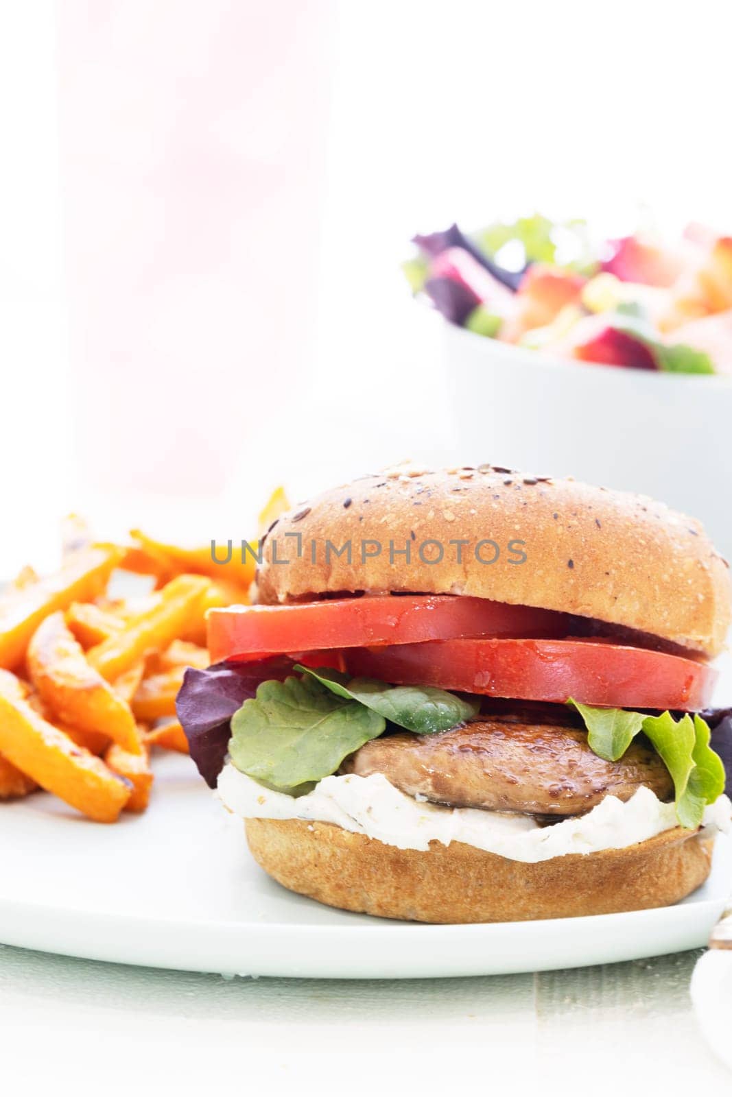 Grilled portobello mushroom burger on whole wheat bun with sweet potato fries.