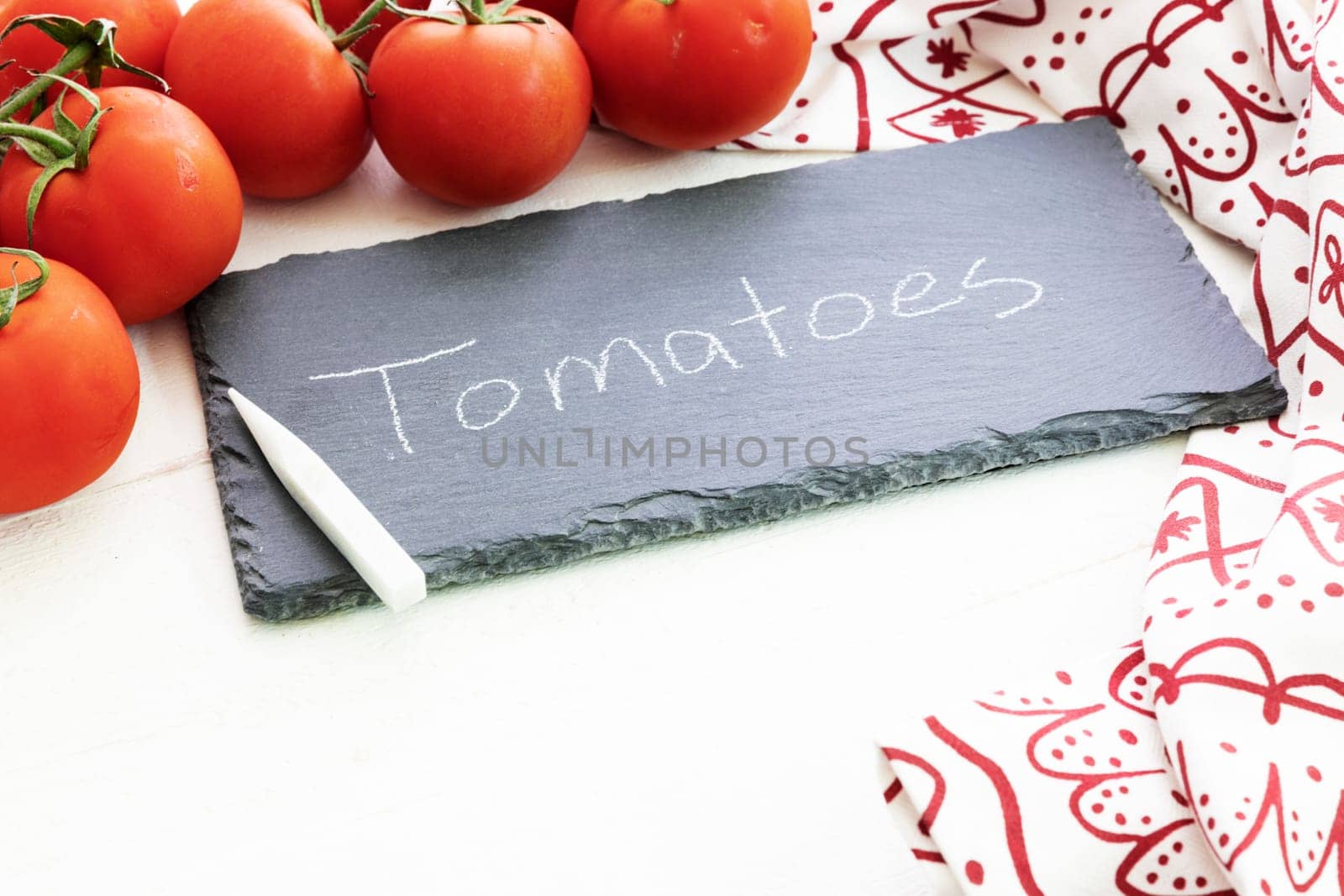 Fresh tomatoes and a chalkboard sign with tomatoes written on it.