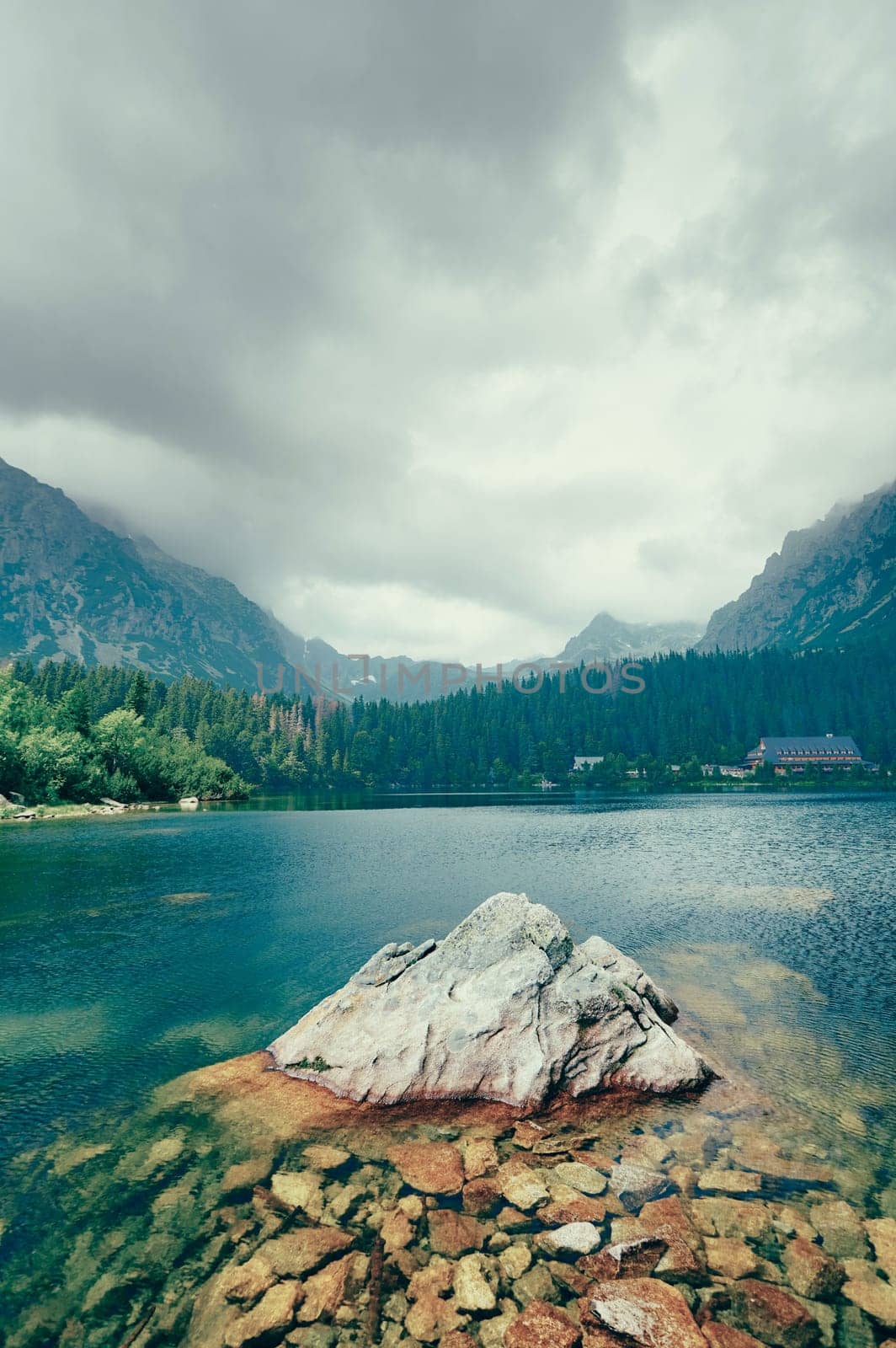 Peaceful mountain lake with big rock in water. Beauty world. Artistic picture.