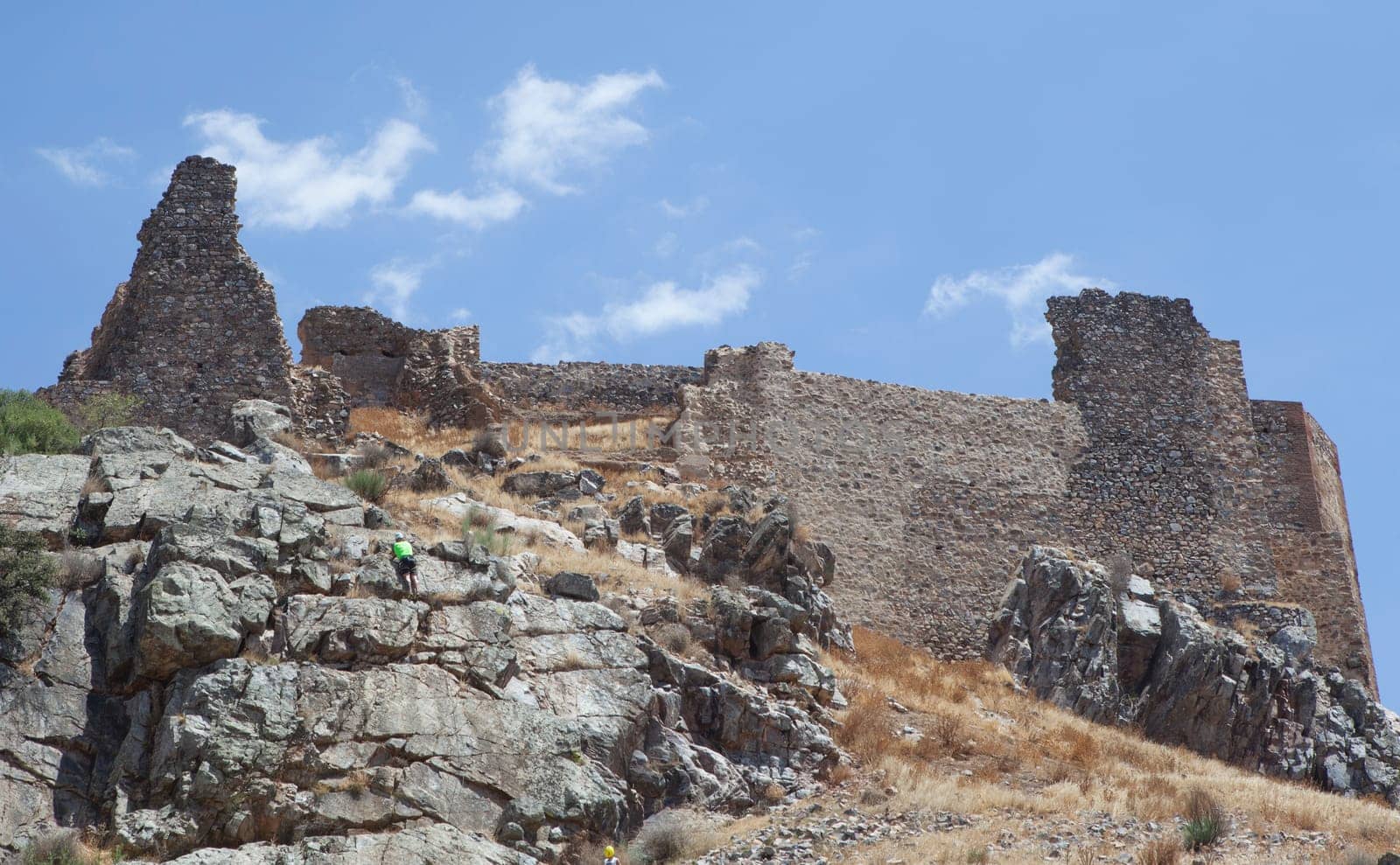 Rock climber ascending Magacela Castle hill. La Serena District, Extremadura, Spain