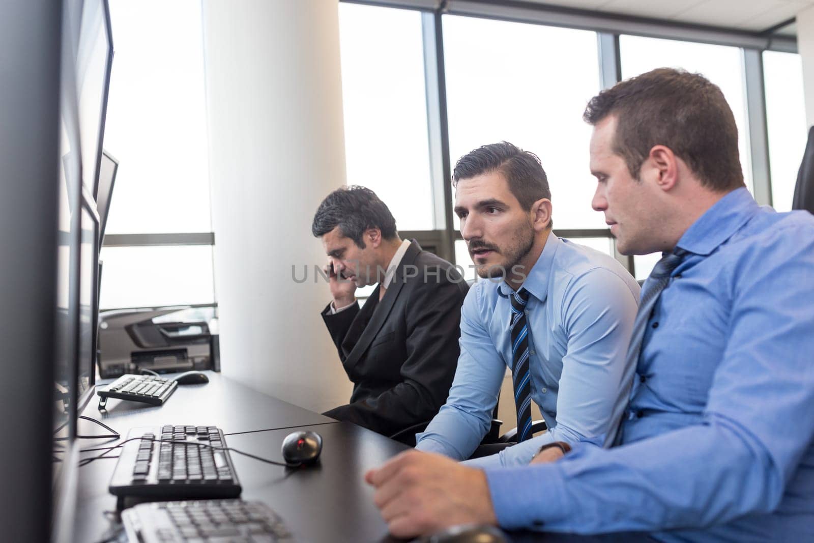 Worried business team brainstorming in corporate office. Stock traders looking at graphs, indexes and numbers on multiple computer screens in time of bear stock market. Crisis management.