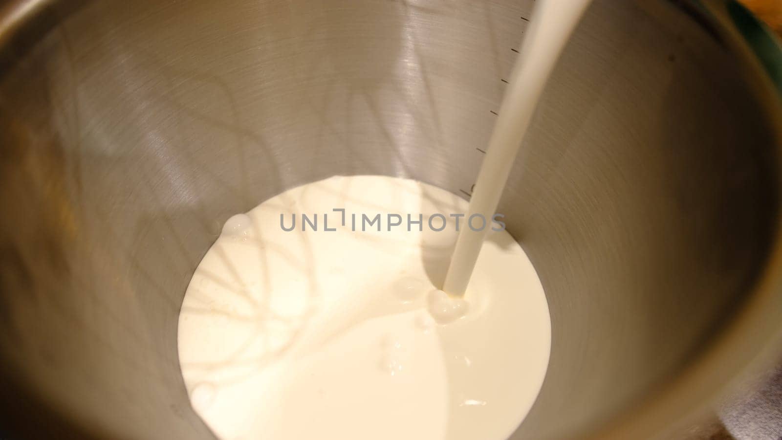 Whipping cream whites in food processor. Hands of professional male chef adding cream to the bowl of modern silver kitchen stand mixer.