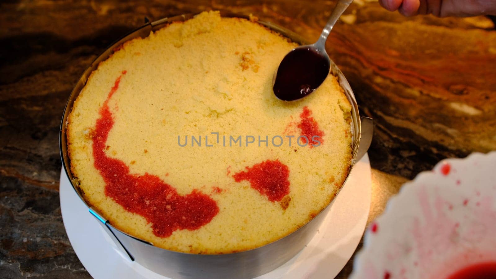 close-up of making a cake. impregnation of sponge cake with red cherry juice