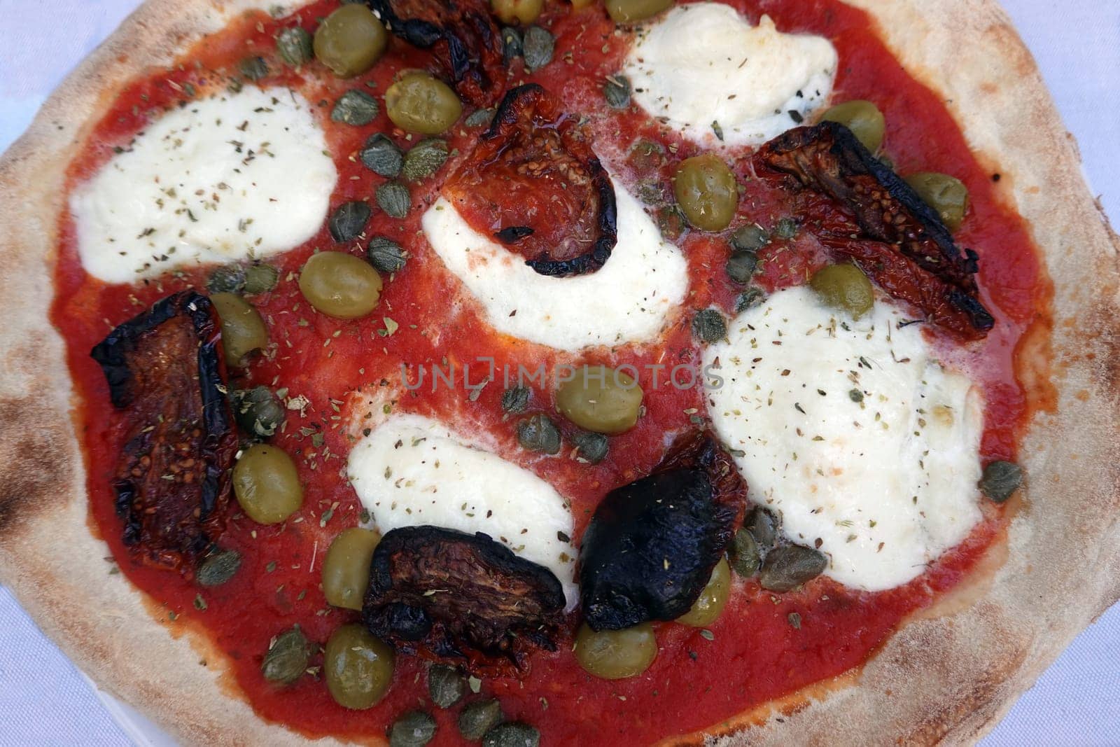 Pizza mit Büffelmozarella, Kapern, Oliven und getrockneten Tomaten