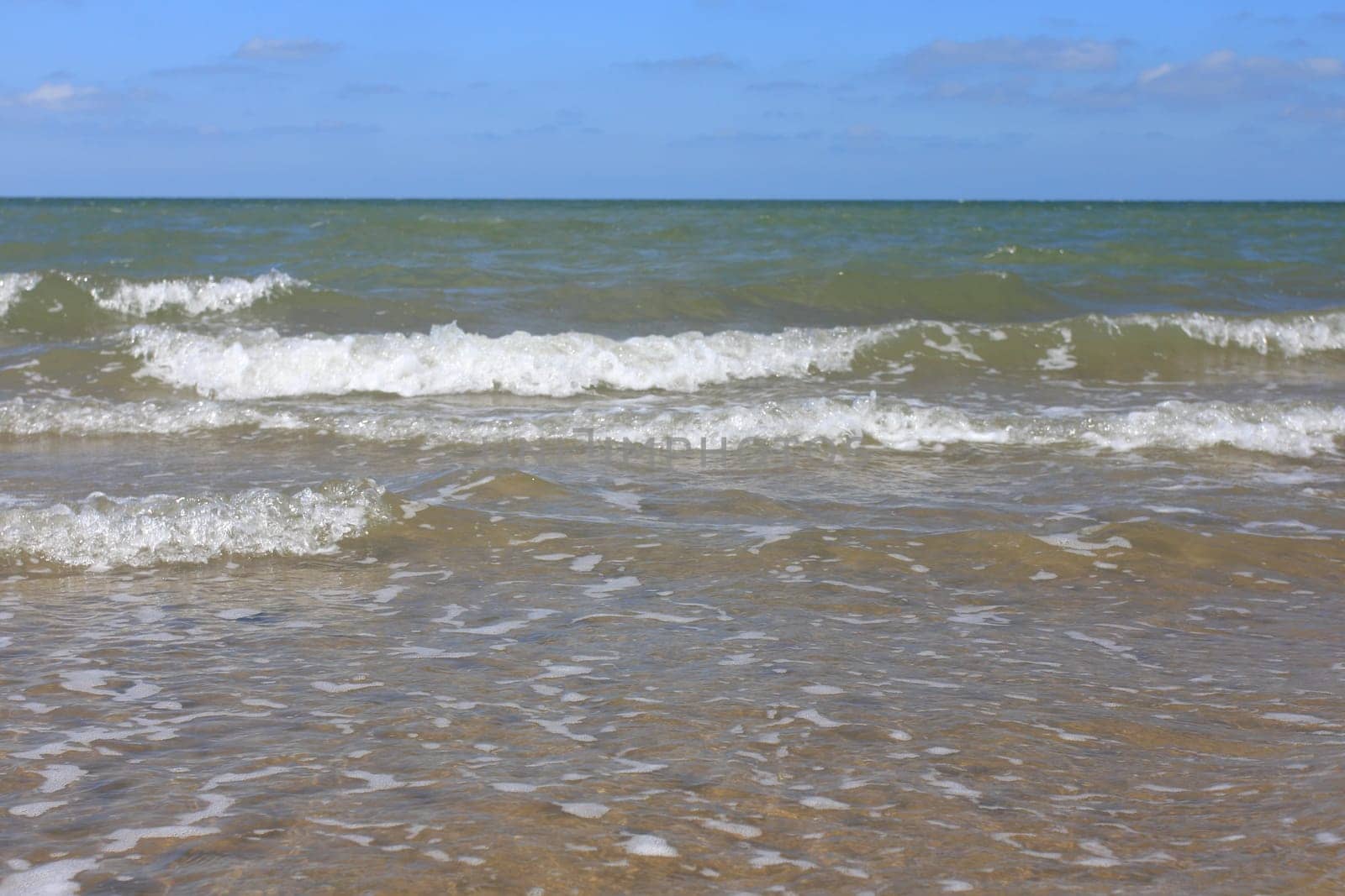 Waves with whitecaps flood the sandy beach.Wellen mit weißen Schaumkronen überfluten den Sandstrand .