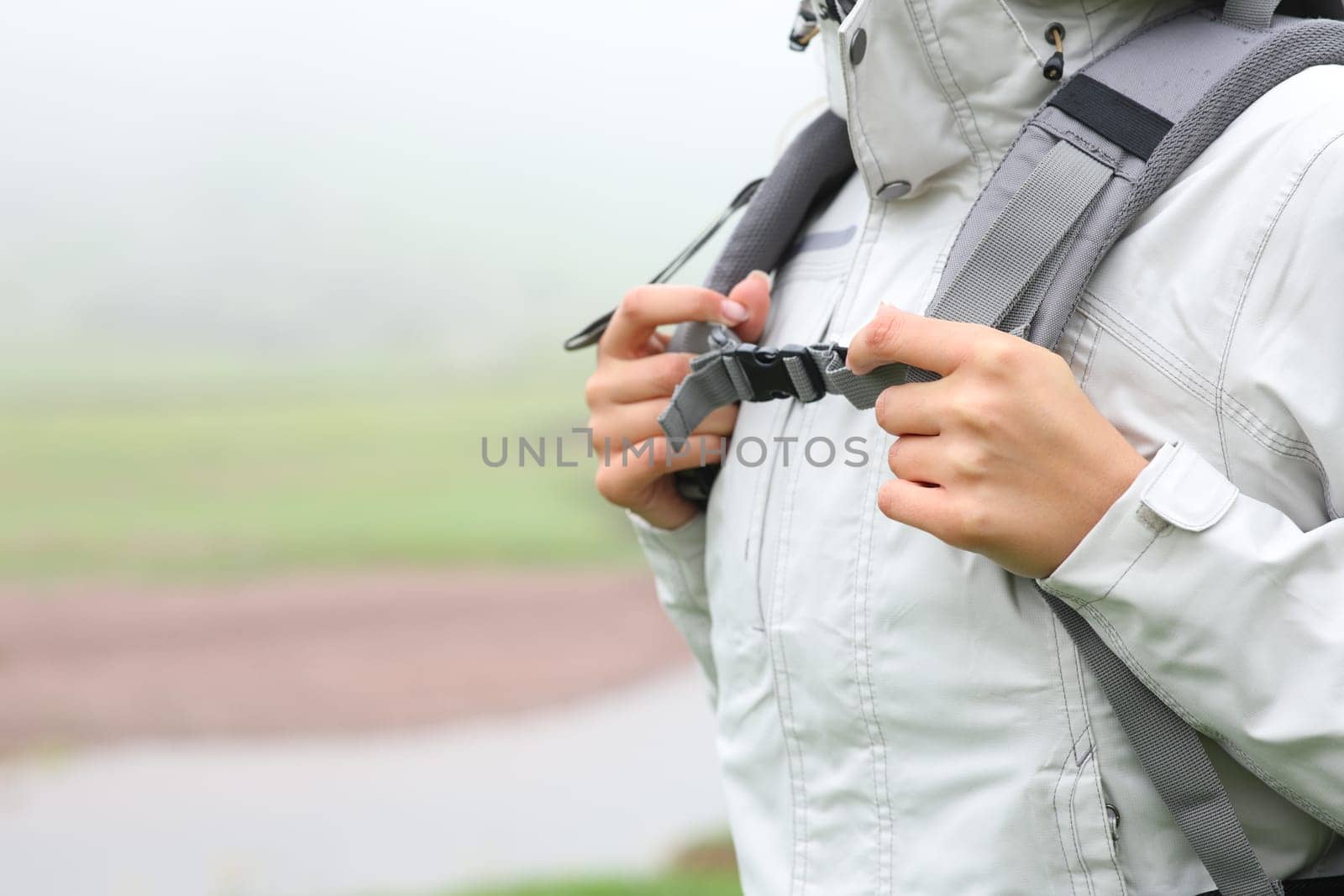 Close up of a hiker hands catching backpack ready to walk in the mountain a foggy day
