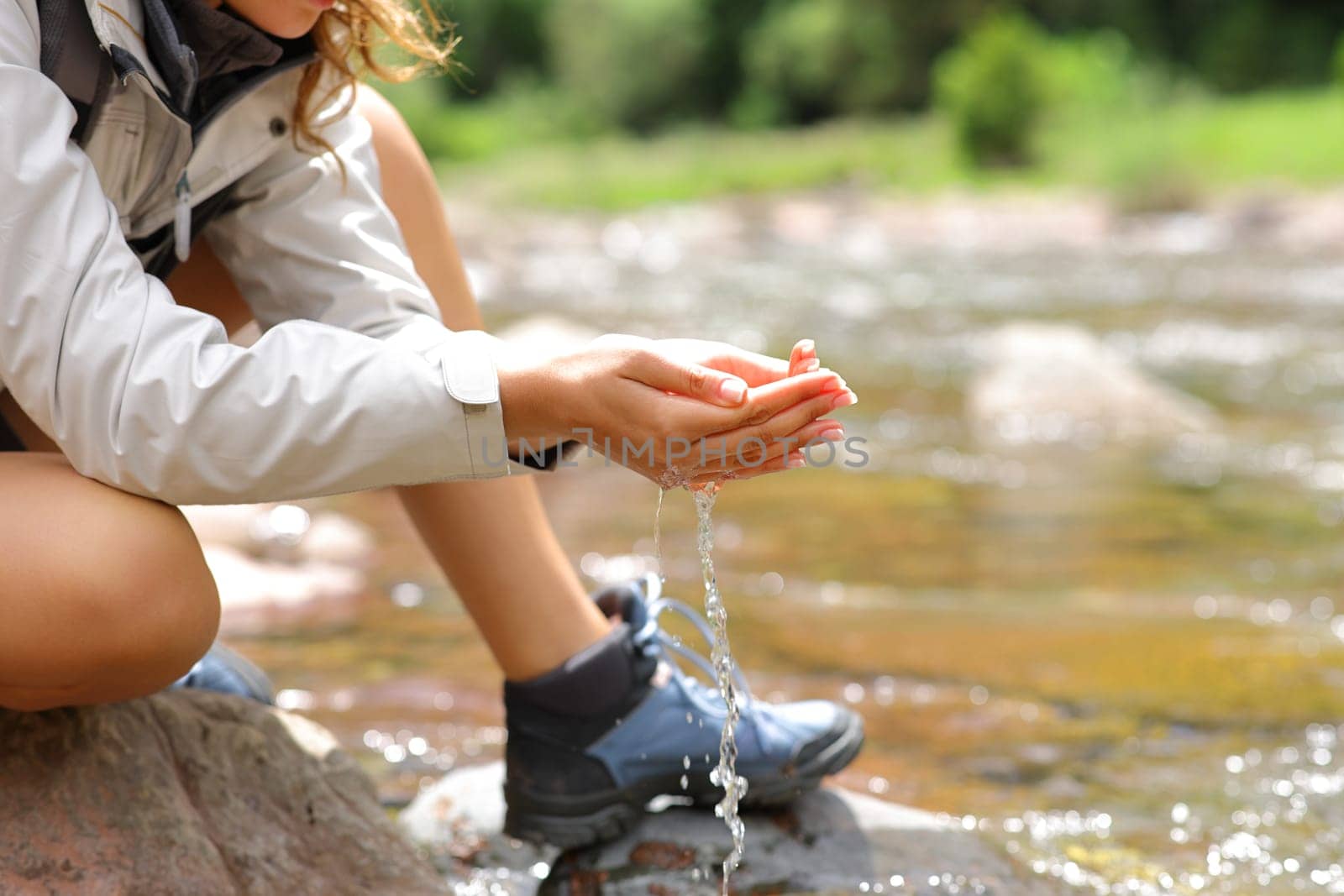 Close up of a trekker with cupped hands catching water from river in the mountain