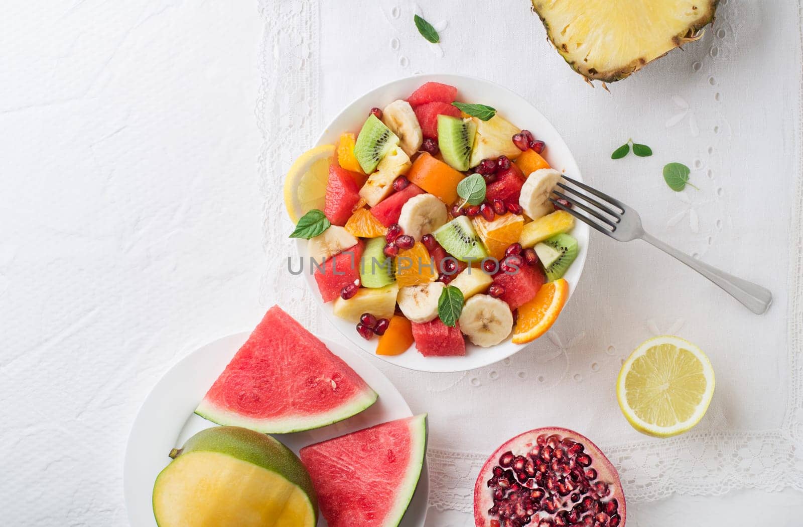Bowl of healthy fresh fruit salad on white background, top view