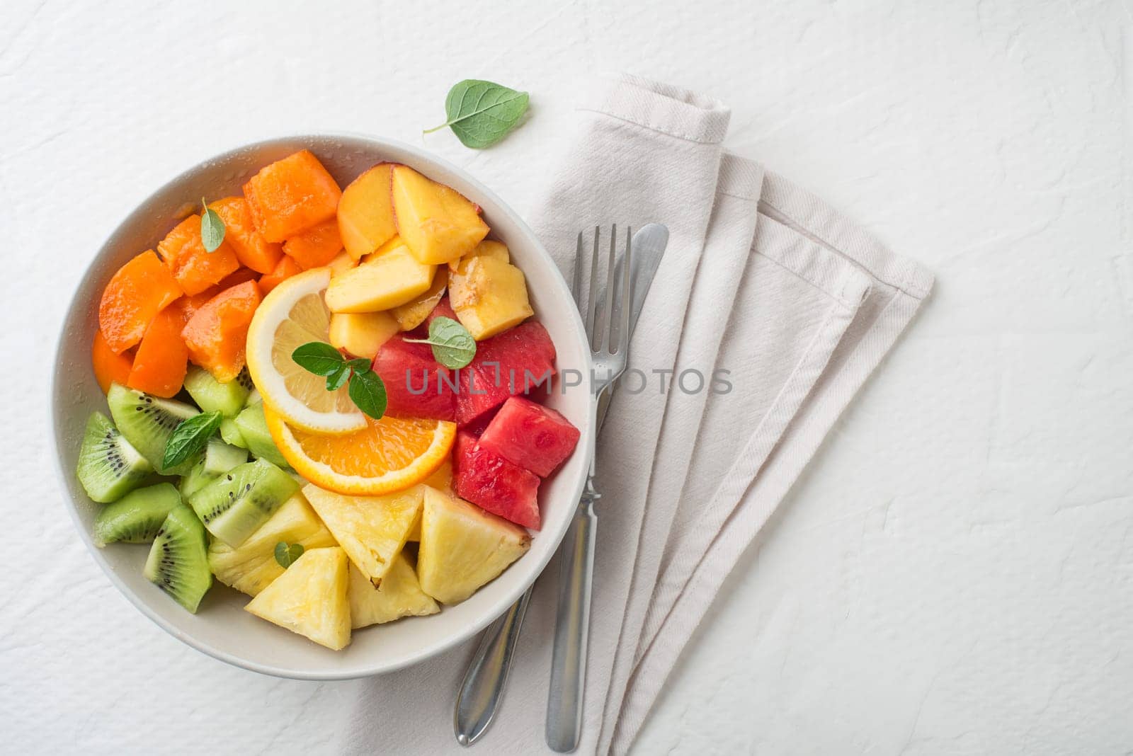 Bowl of healthy fresh tropical fruit salad on white background. Top view.