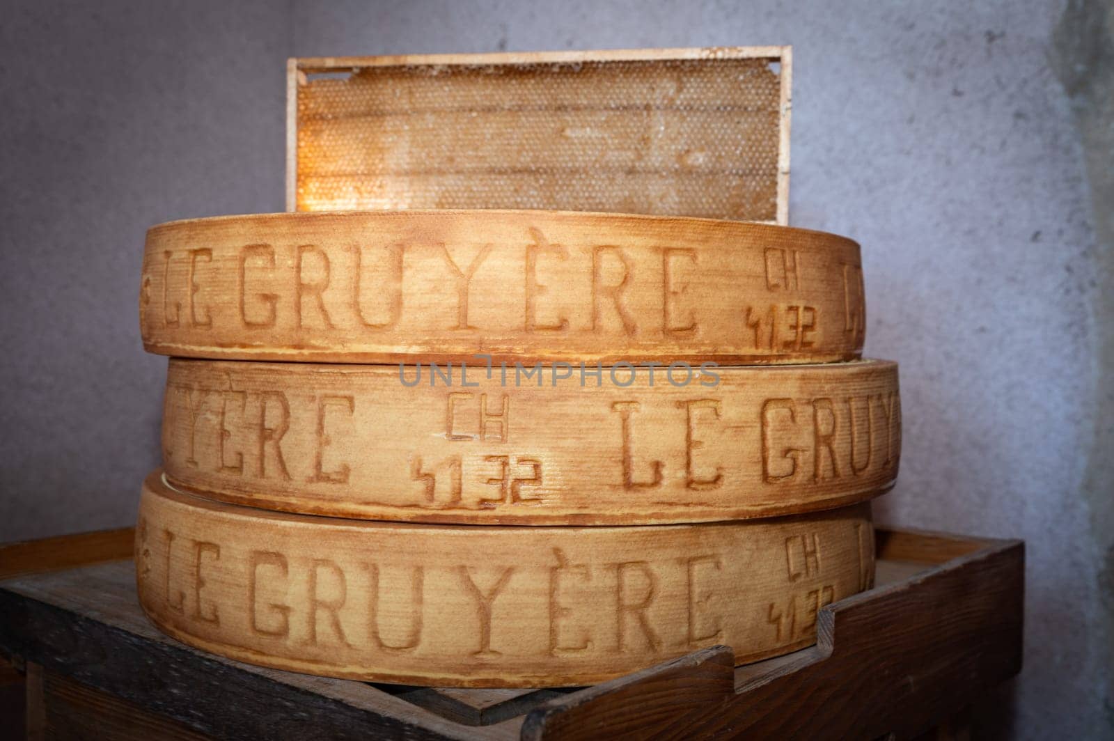 July 11 2022, Lyon, France : stack of wheels of Swiss Le Gruyère PDO cheese in a cellar with a honeycomb