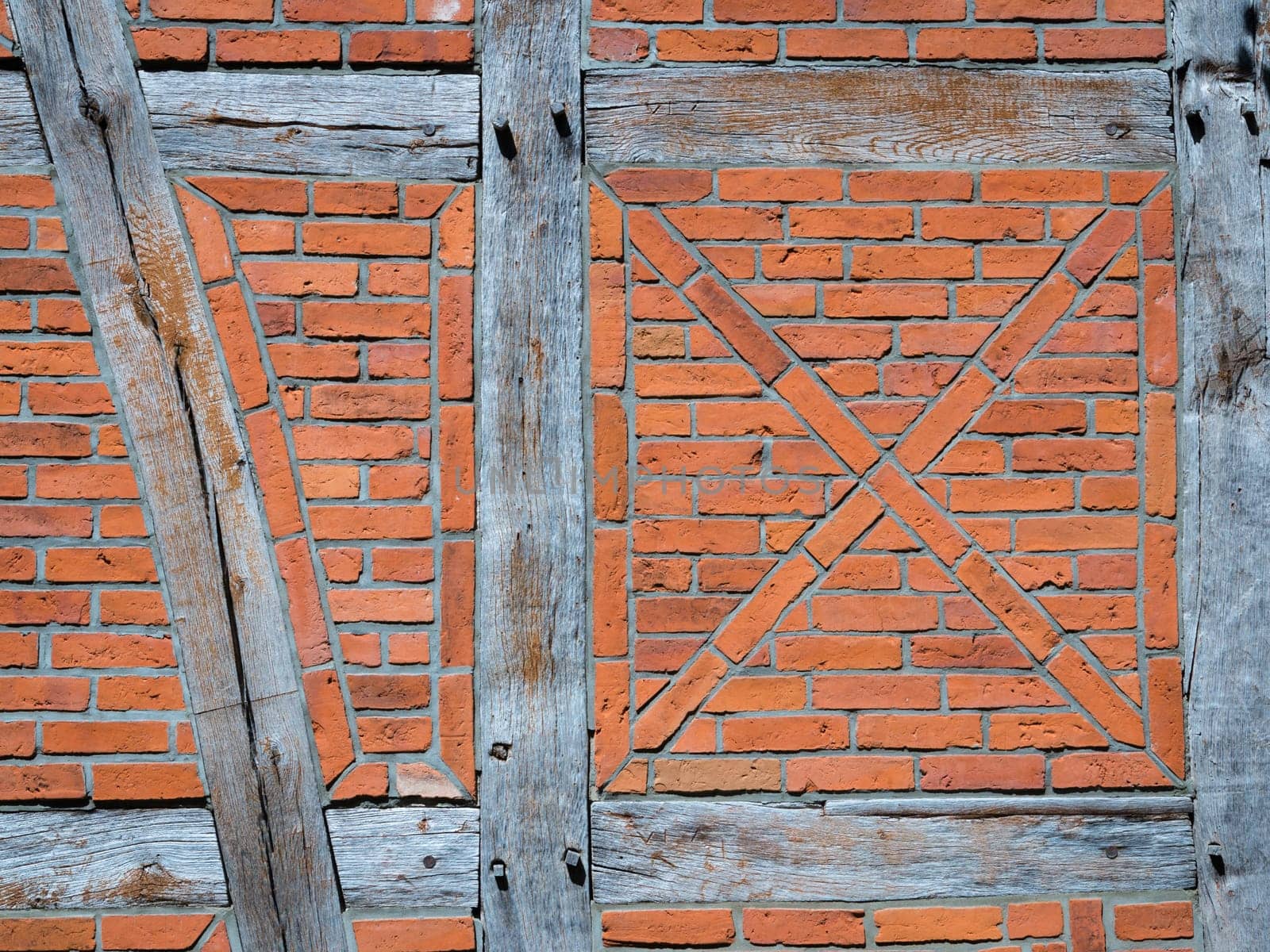 Old wall made of brown half-timbered, bricked with bricks in different shades