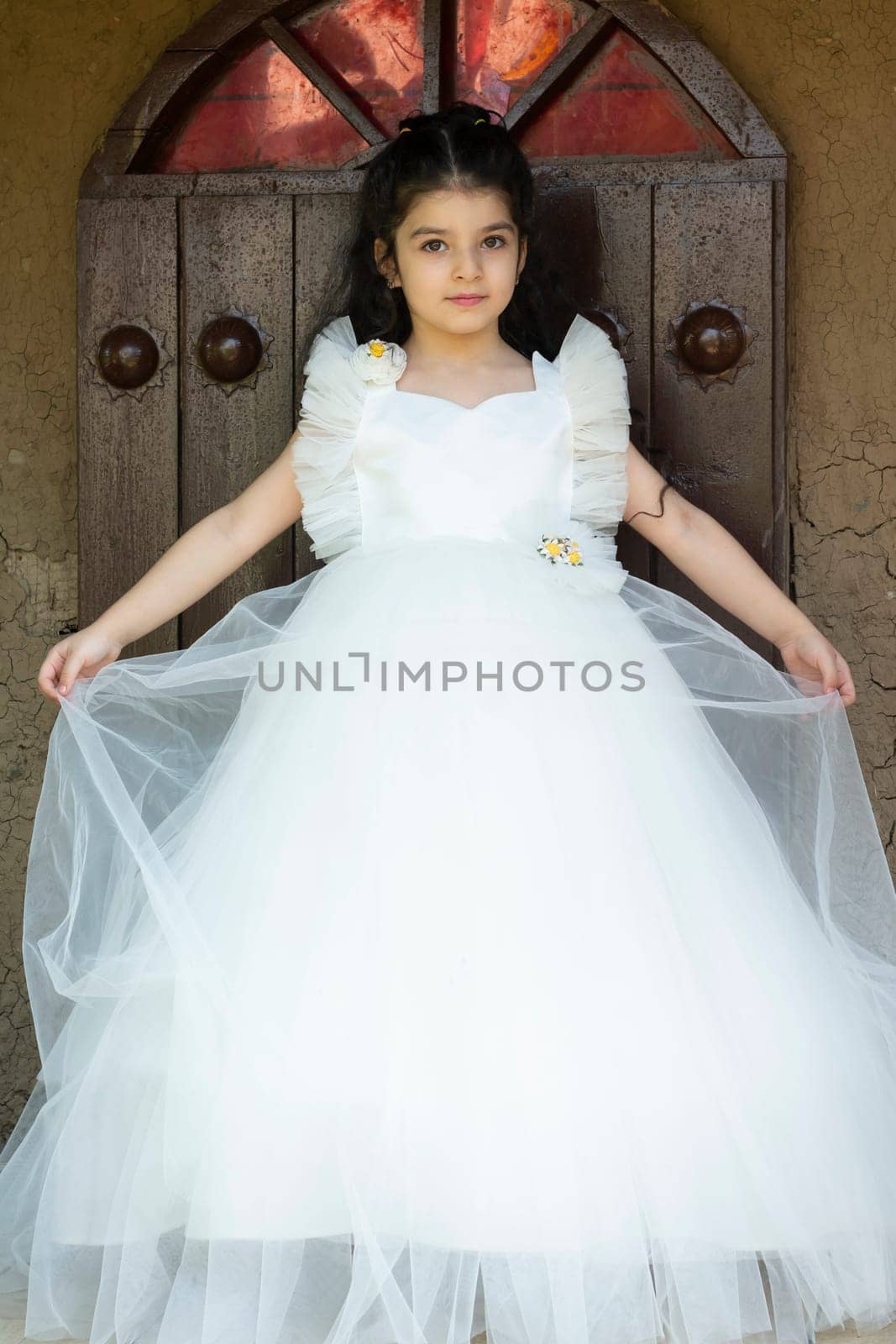 5 years old girl put on a white dress and standing in front of decorated wall